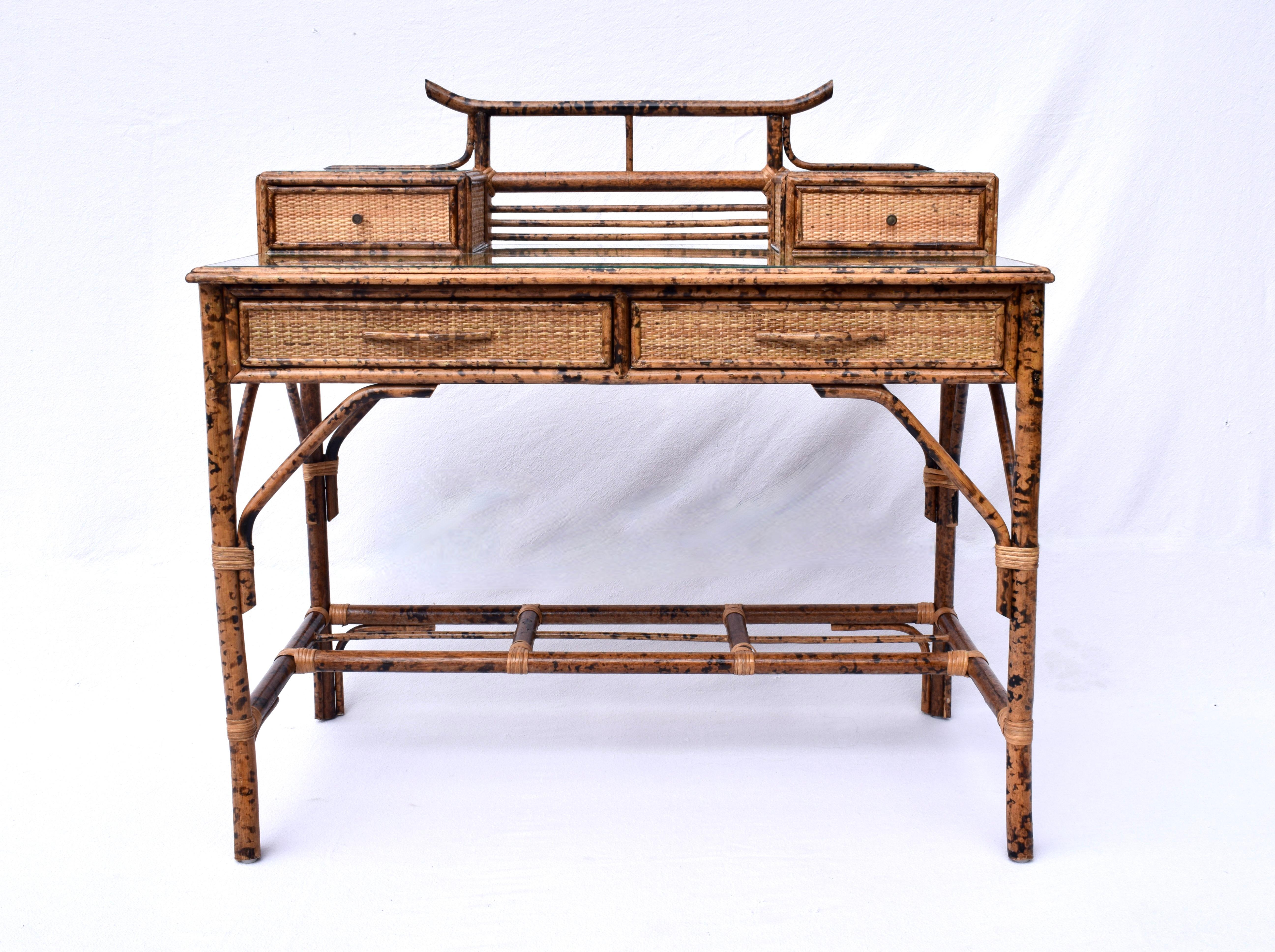 Midcentury burnt tortoise bamboo and grass cloth desk with British Colonial design elements featuring two glove boxes, two drawers, elegant splay front legs and matching caned seat chair. Includes new custom Cowtan and Tout Chinoiserie toile Chintz