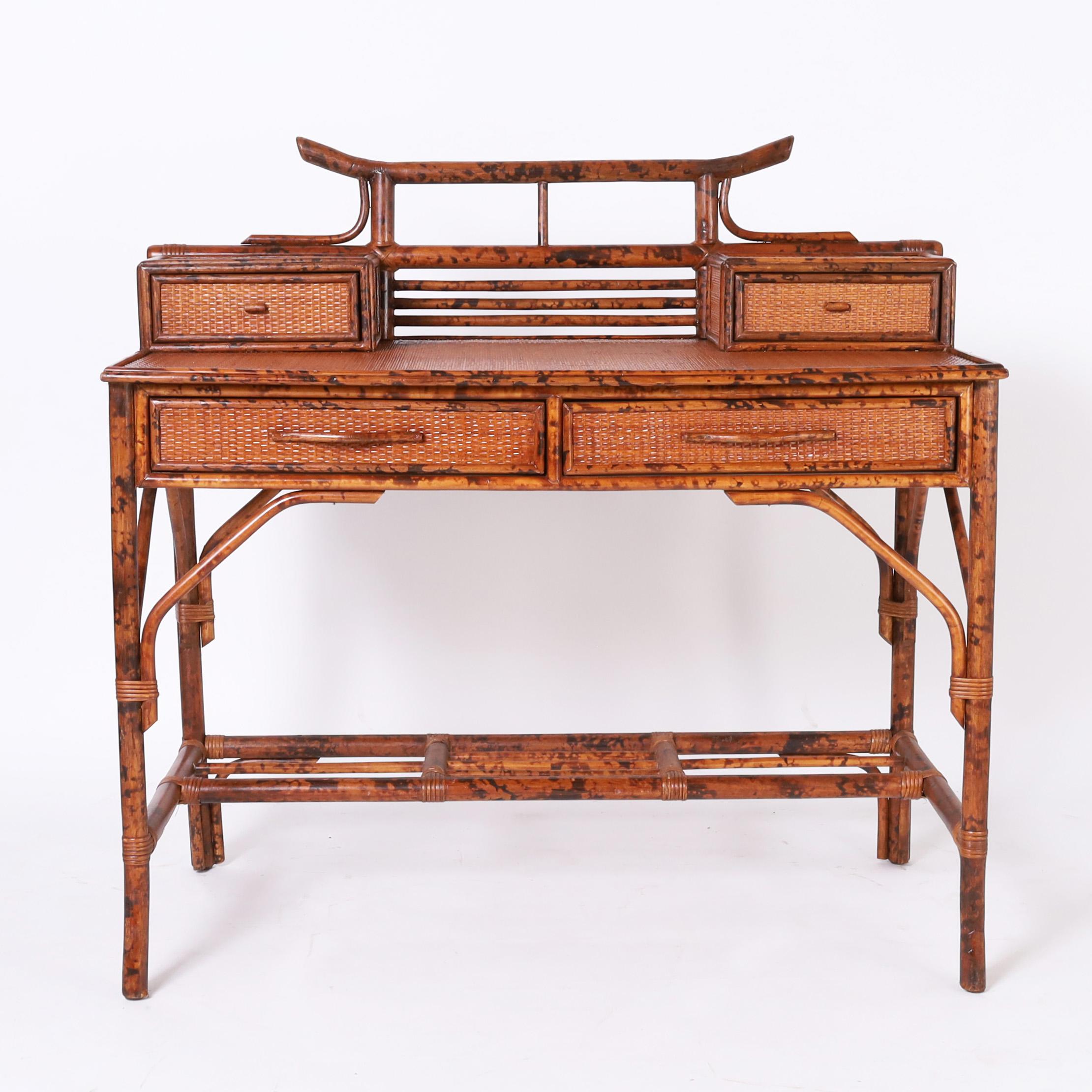 Impressive mid century desk crafted with a faux burnt bamboo frame having grasscloth panels on the tops, sides, and drawer fronts, featuring two glove boxes and a dramatic pagoda form with brackets and splayed feet. 