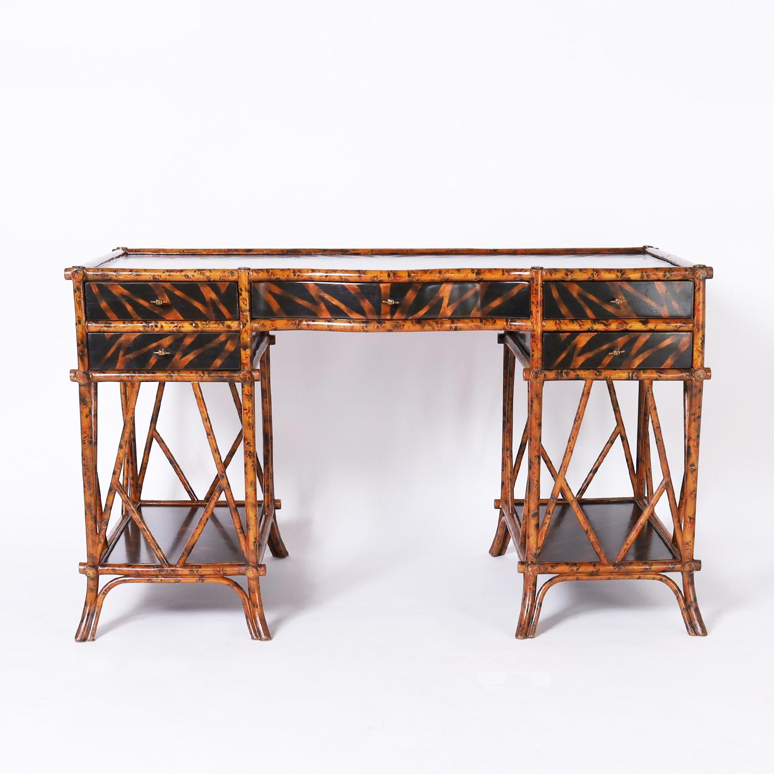 Vintage British Colonial style desk featuring a faux bamboo frame with a faux tortoise finish, lacquered panels hand decorated with a faux jungle motif, brass fist and stick hardware and splayed feet. Signed Maitland-Smith in a drawer.