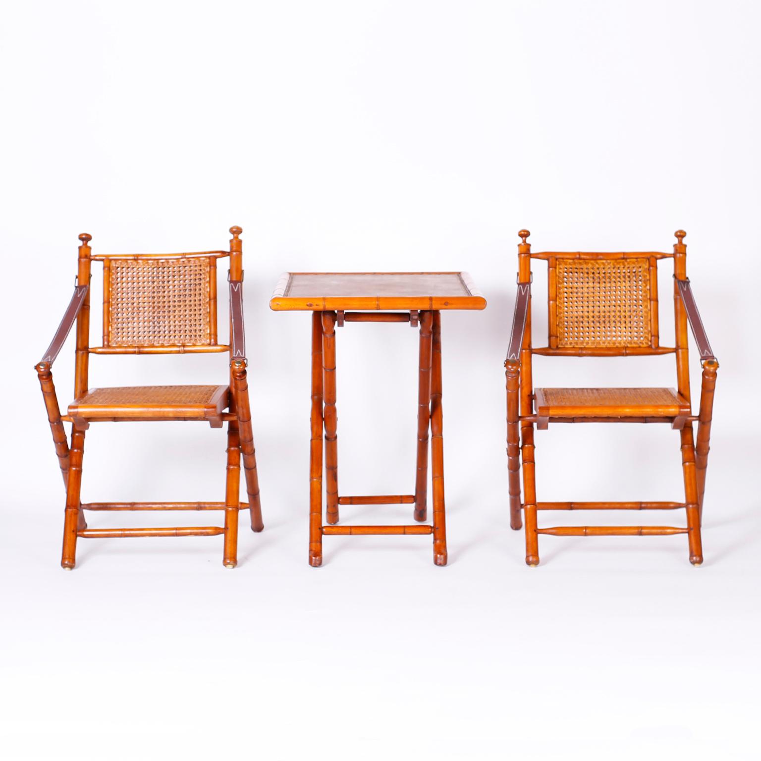 Campaign style folding chairs and table crafted in mahogany featuring turned faux bamboo frames, canned seats and double canned backs, leather straps and metal caps. The table has a leather top bordered with tacks.
Measures: Chairs: H 34, W 22, D