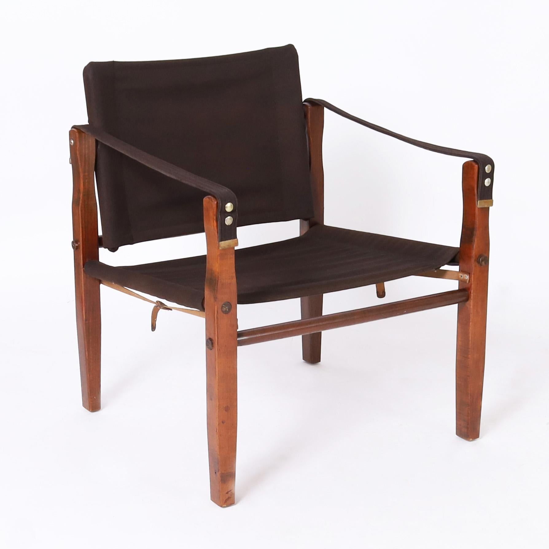Dashing set of four vintage British Colonial chairs crafted in mahogany stained maple with a pegged construction in a safari style having classic sling upholstered arms, seats and backs in a durable cotton fabric.