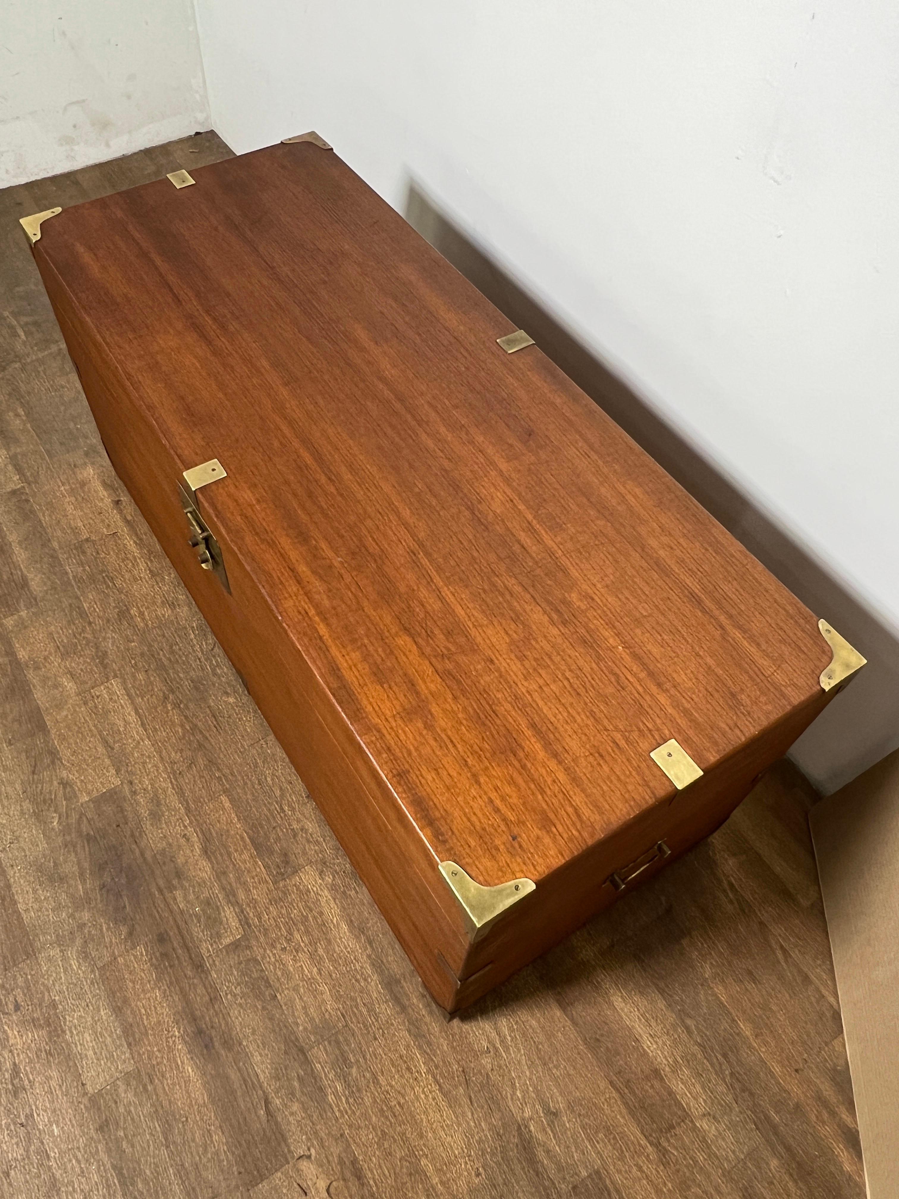 Una grande cassapanca in teak in stile Bristish Coloni, circa 1950. Maniglie e ferramenta di sollevamento in ottone massiccio. Questo baule è servito come tavolino da caffè per diverse generazioni di una famiglia che lo ha utilizzato per riporre la