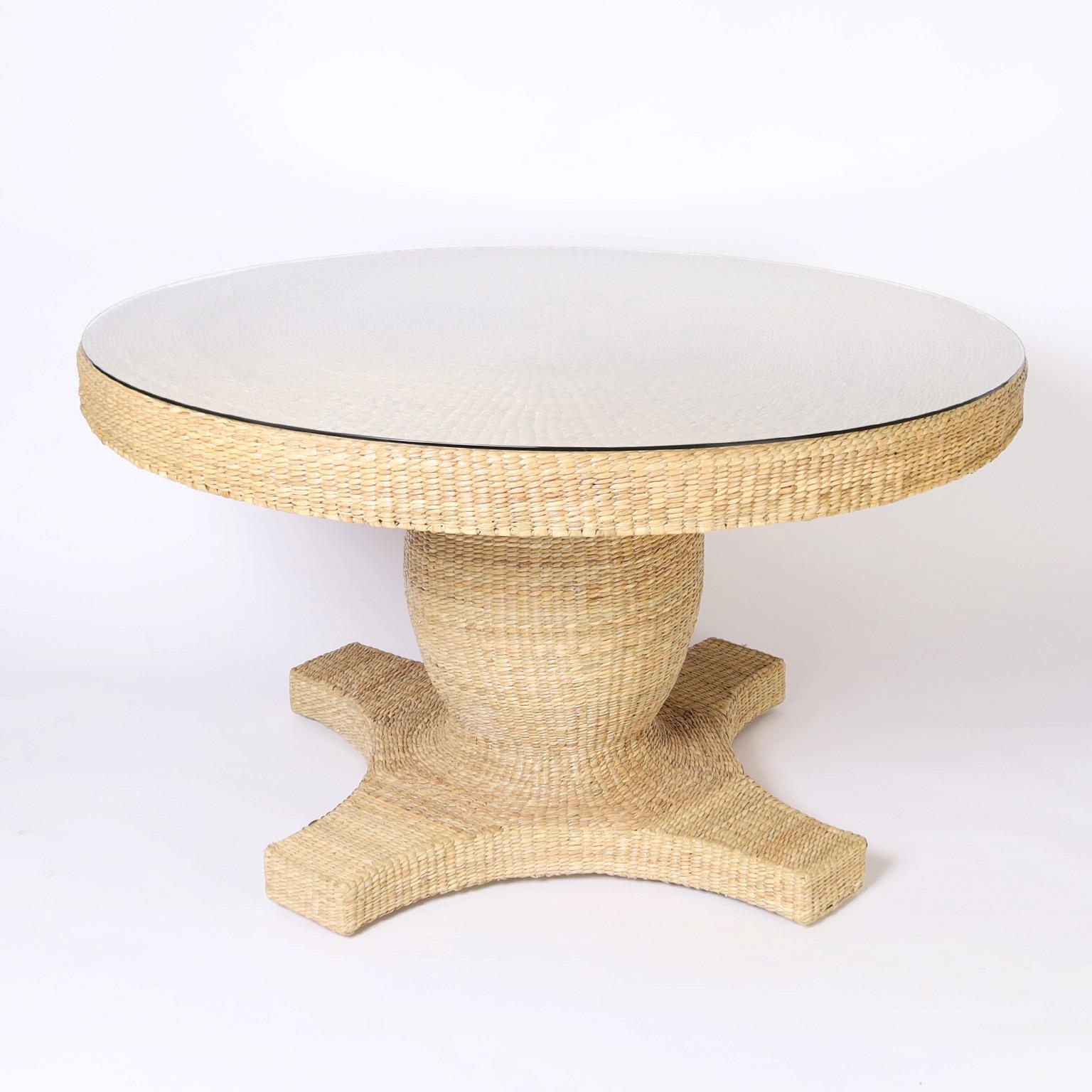 British Colonial style wicker round dining table crafted in woven reed over a sturdy metal frame featuring a spiral woven top and a classic pedestal form. One of many designs from our Flores Collection designed and offered exclusively by F. S.