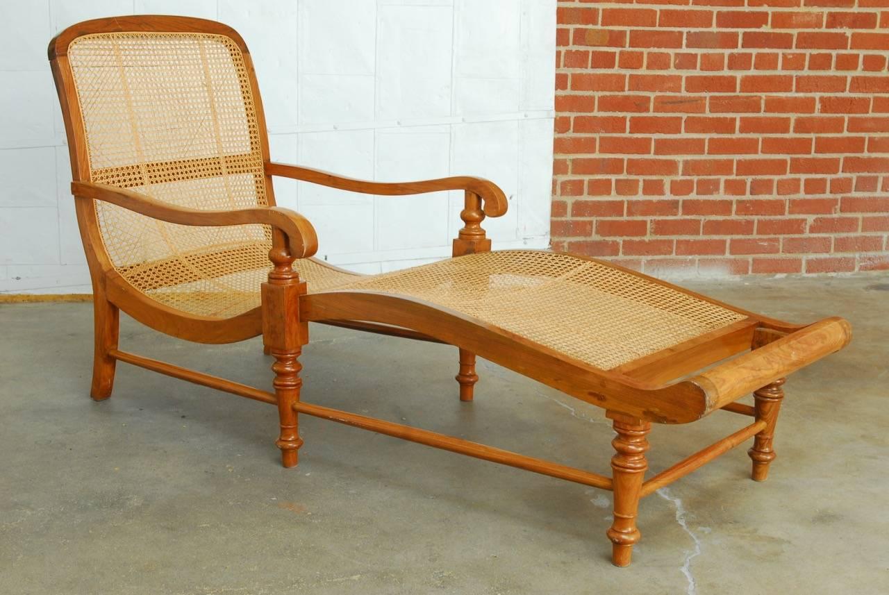 Stunning British Colonial chaise longue or longue constructed from radiant grained teak. Beautifully made with a wave like curved frame and long graceful arms. Supported by six legs conjoined by stretchers and the front four being turned. The front