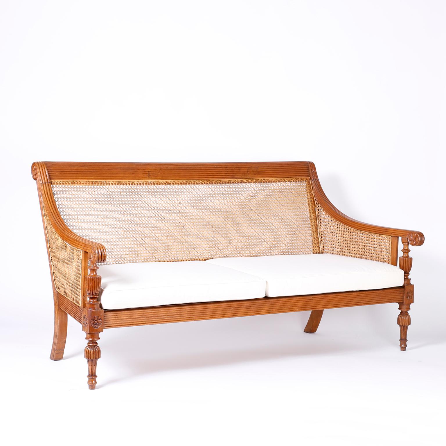 Antique Anglo-Indian sofa crafted in teak wood with pegged construction carved and beaded frame, caned back and seat and Classic carved, turned legs.