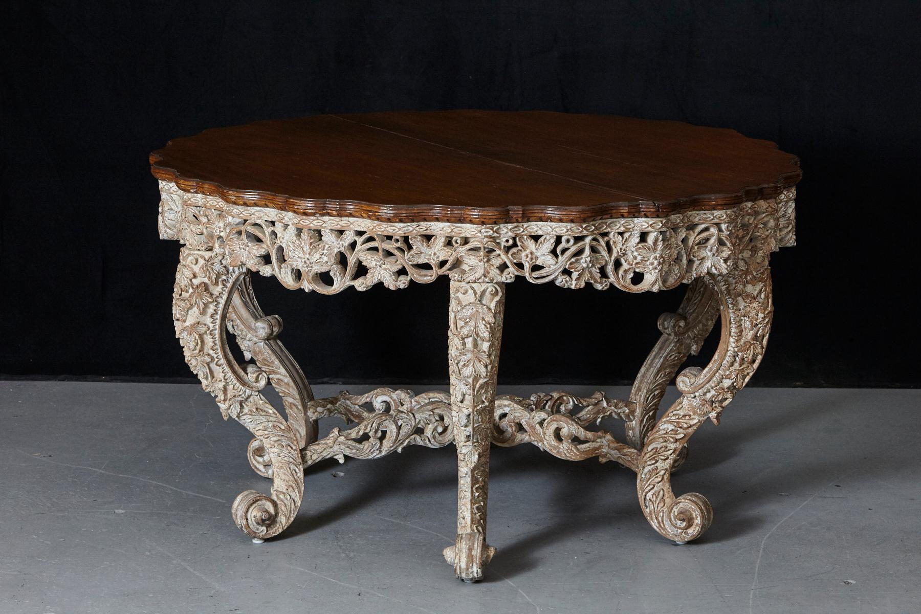 A stunning Anglo-Indian centre table with six legs, beautifully carved in elaborate fashion. Carved and pierced apron with foliate designs, six cabriole legs with rich floral carvings and terminate in left scrolls on a peg foot joined by carved and