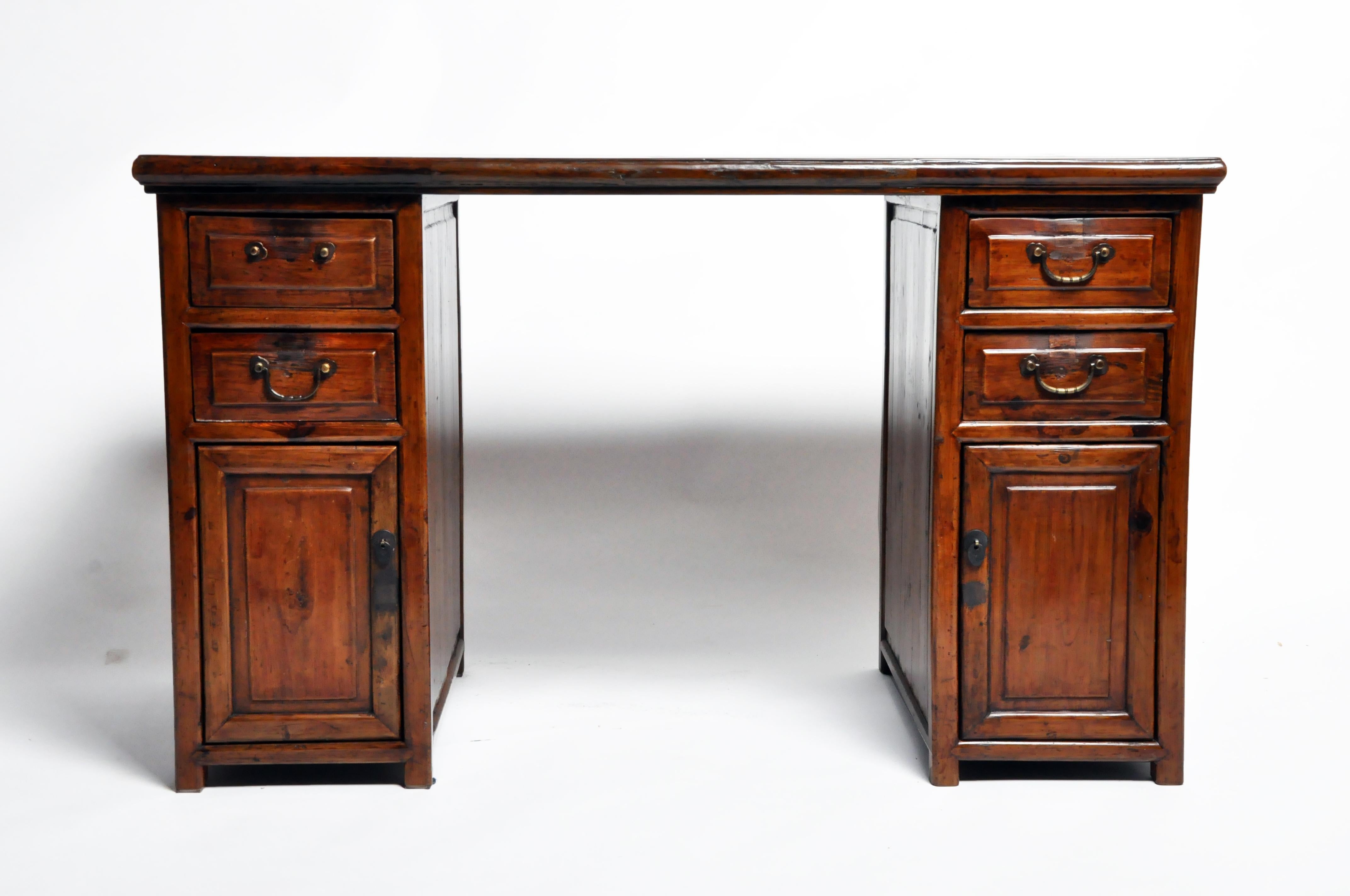 This handsome British Colonial desk is from Thailand and was made from wood, circa 20th century. The desk features four drawers and two doors for additional storage space. Wear consistent with age and use.
   