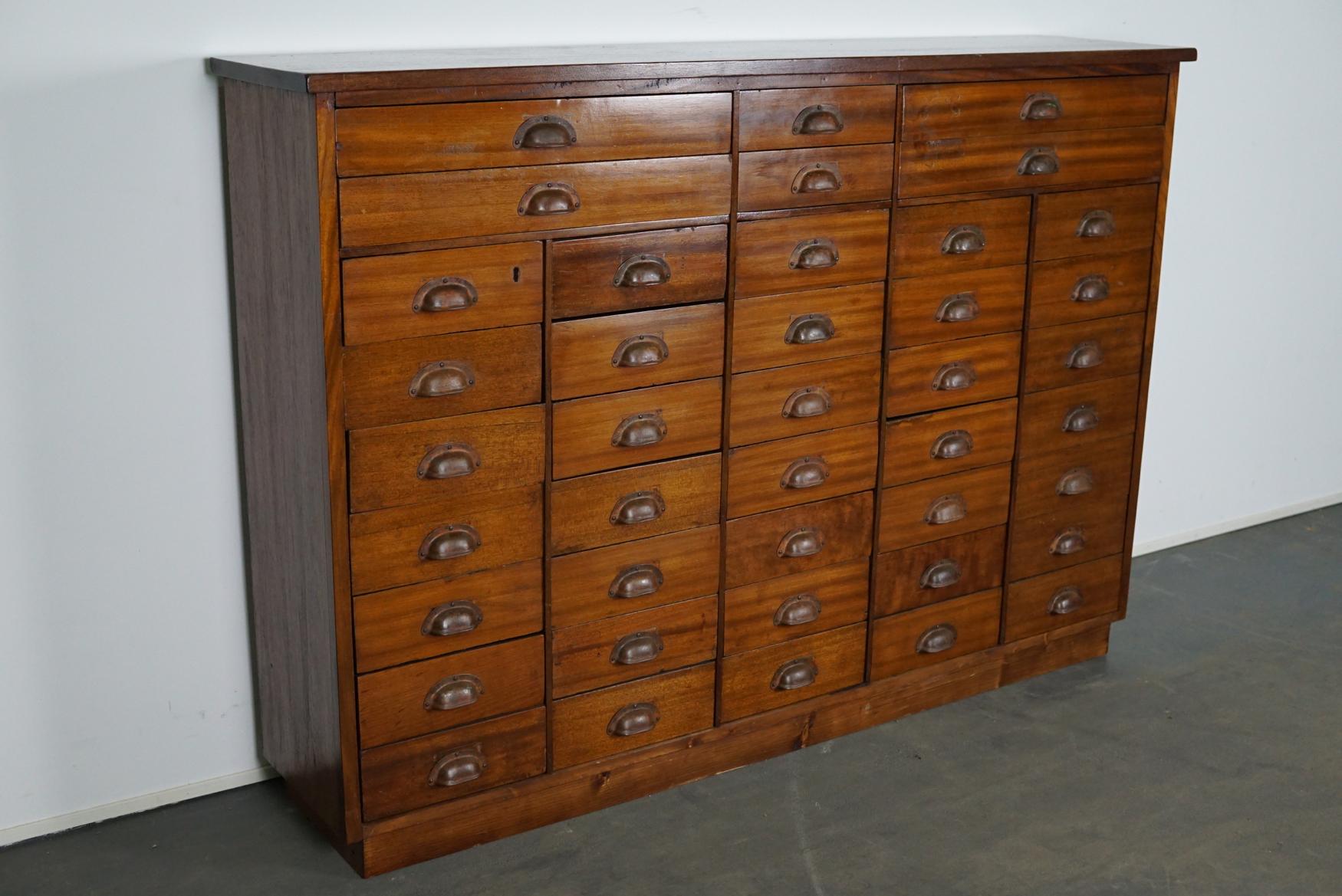 This vintage mahogany bank of drawers dates from the 1930s and was made in England. It features a solid wooden frame, the drawers are mahogany veneered with metal cup handles.