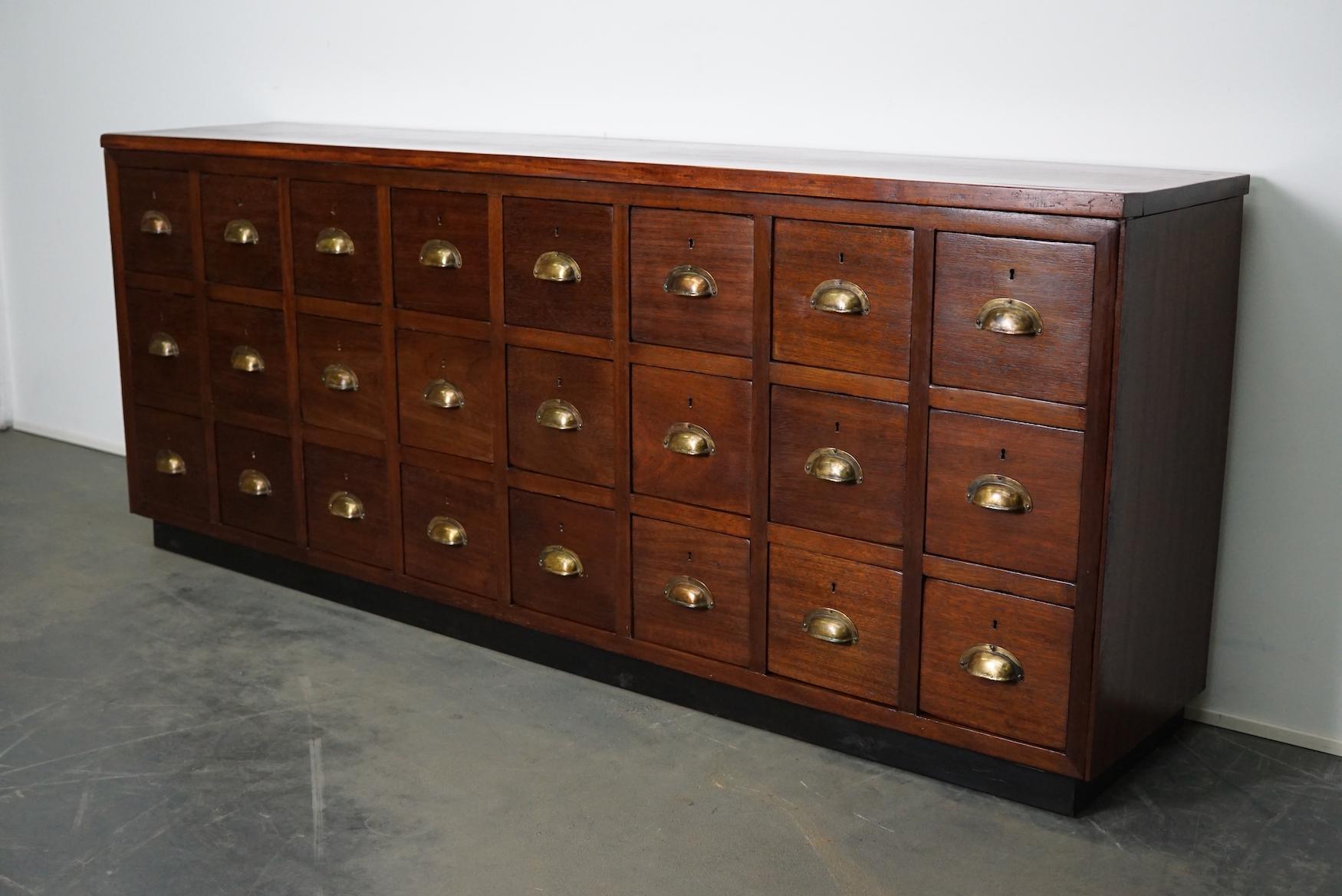 This vintage mahogany bank of drawers dates from the 1930s and was made in England. It features a mahogany frame, tropical hardwood top and drawers with mahogany fronts and brass cup handles. There are no keys of the drawers present.