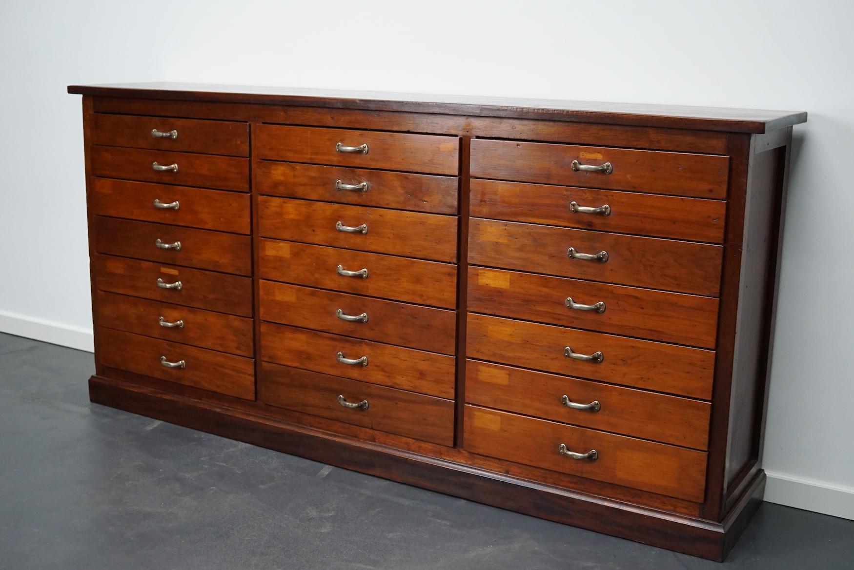 This vintage mahogany bank of drawers dates from the 1930s and was made in England. It features a mahogany frame, top and drawer fronts with metal handles. The interior dimensions of the drawers are: DWH 29 x 51 x 5 and 7 cm. We have two identical