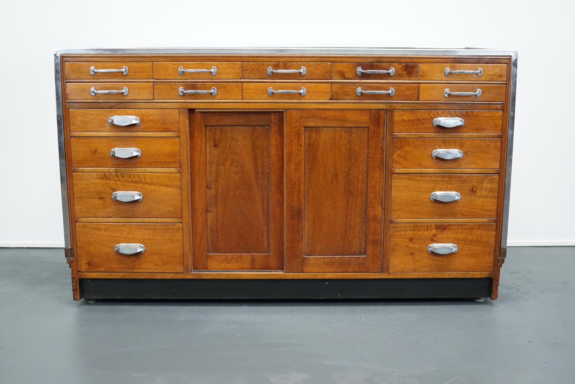 This vintage mahogany haberdashery shop counter with walnut veneer sides and palissander details dates from the 1930s and was made in England. It features a solid wooden frame and drawers in mahogany with art deco style handles.