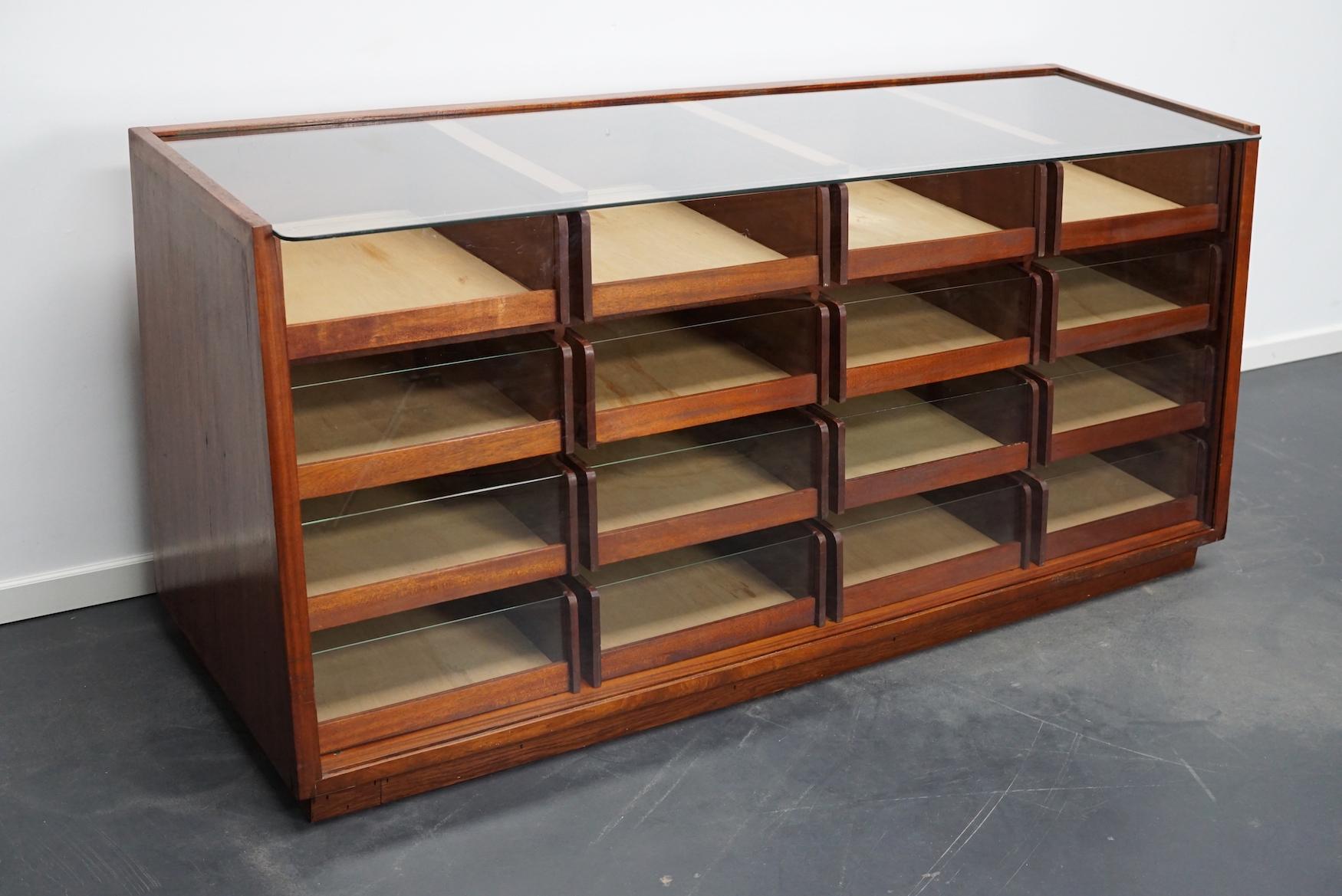 This vintage mahogany haberdashery shop counter dates from the 1950s and was made in England. It features a solid frame, glass casing and drawers in mahogany with brass handles. The drawers measure +- DWH 47 x 39 x 13 cm.