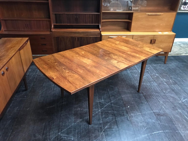 This is a truly beautiful dining table in rosewood by the high-end English maker Alfred Cox. Some of the design features to look out for are the gentle curve to the table’s ends, the tapering legs and the little ‘rebate’ that runs around the edge of