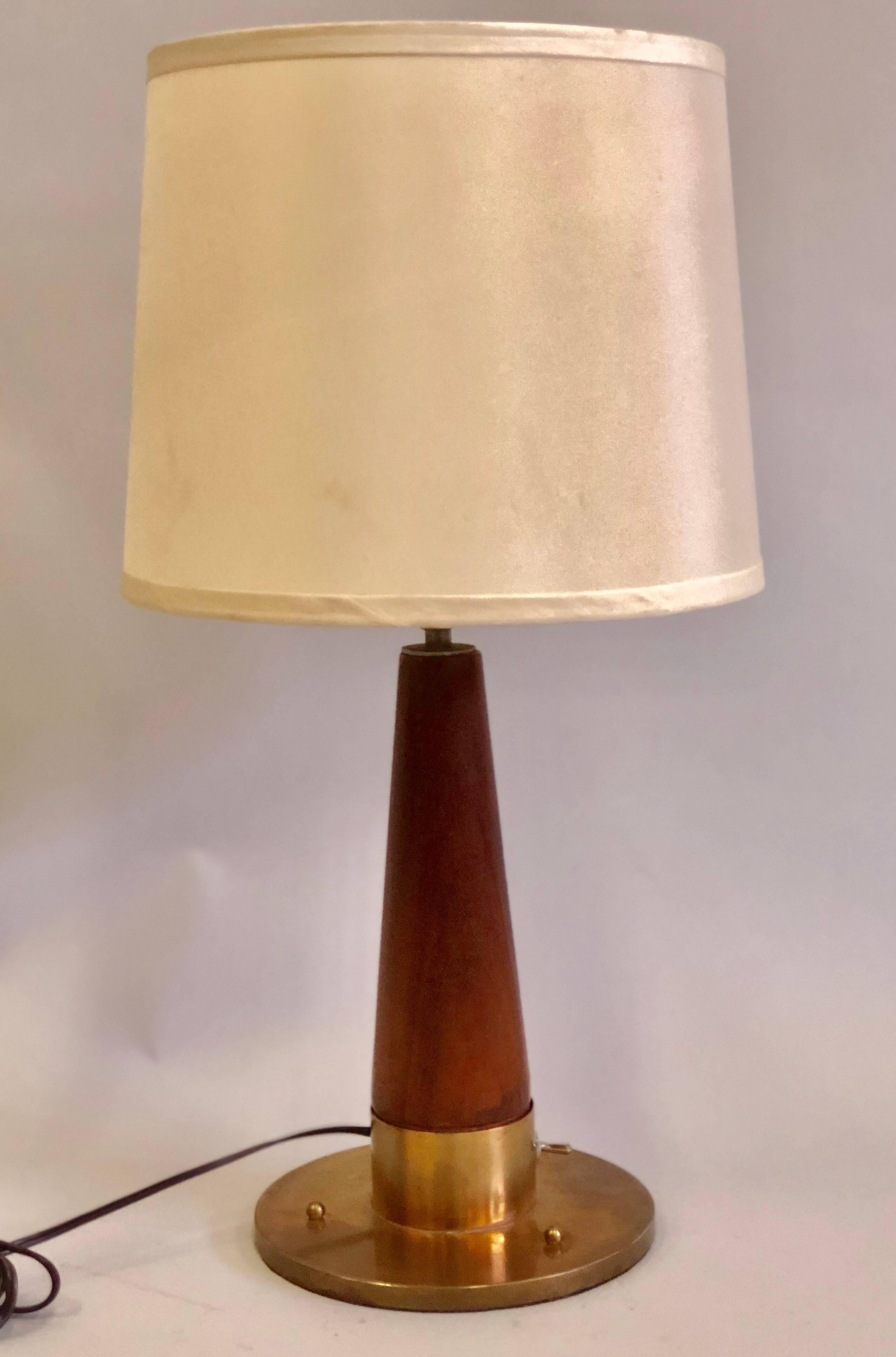 Elegant British midcentury teak and brass desk or table lamp from a luxury marine vessel featuring an elegant round brass base and a tapered teak stem finished with brass banding around the lower and upper parts of the teak stem. Brass ball finials
