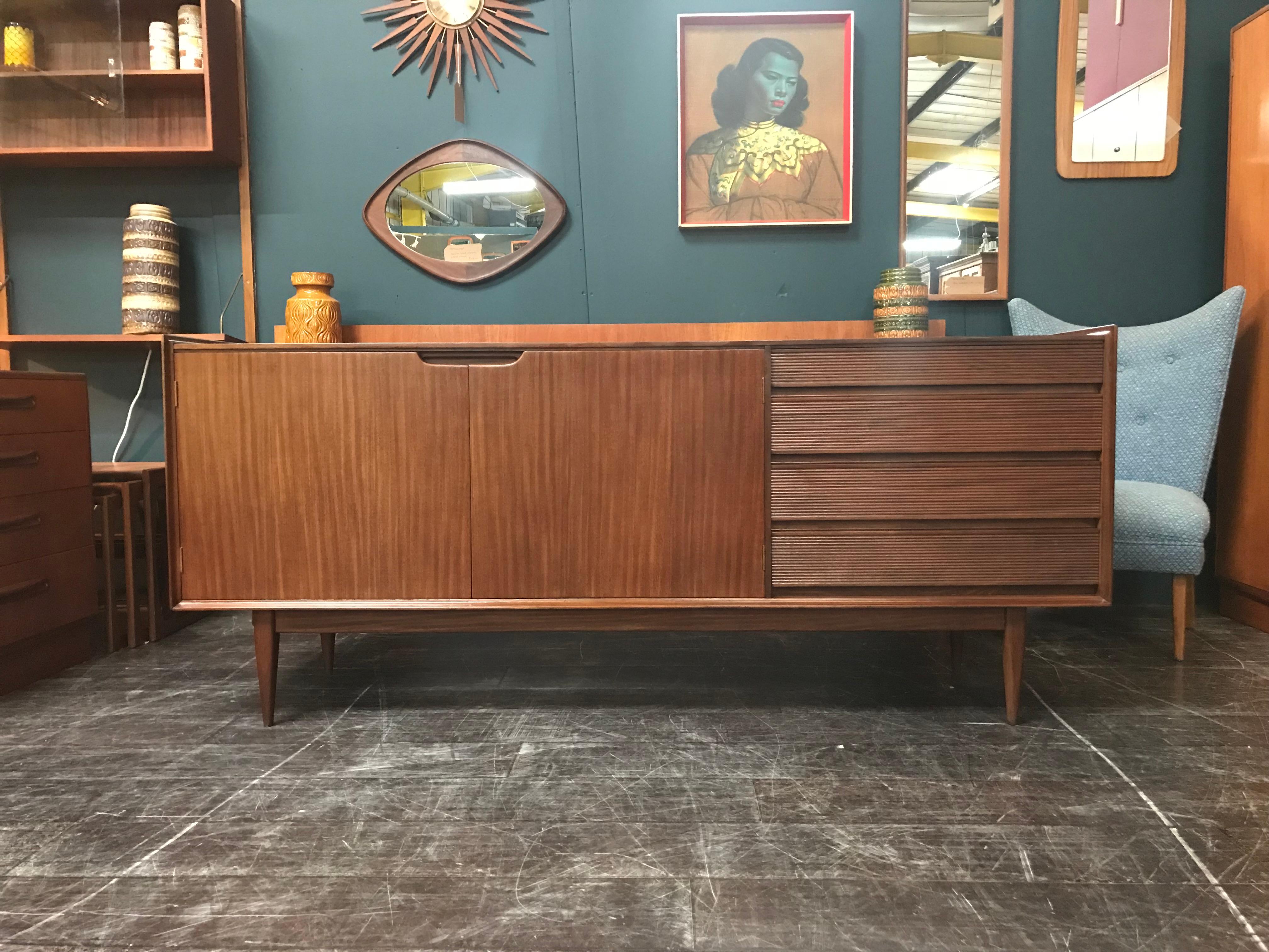 This midcentury sideboard was designed by Richard Hornby and manufactured by Fyne Ladye during the 1960s. It’s a finely crafted, high quality credenza made from solid afrormosia, which makes it unusually heavy. The sideboard features four drawers