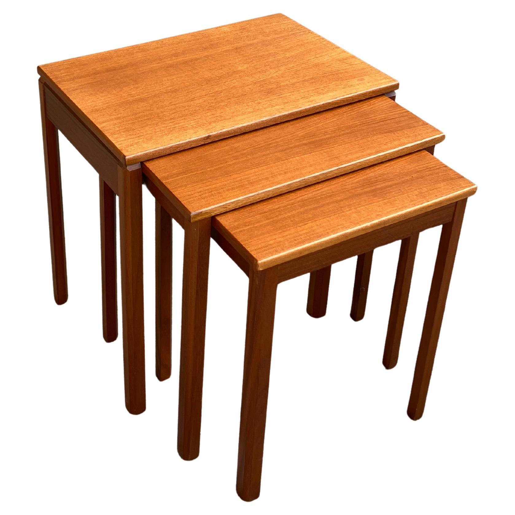 This is a beautiful mid-century set of three coffee tables by A.H McIntosh & Co Ltd, Kirkcaldy, Scotland. This solid teak nesting table set is elegant, with subtle details such as hexagonal legs and shaped edges. The teak has a lovely colour and