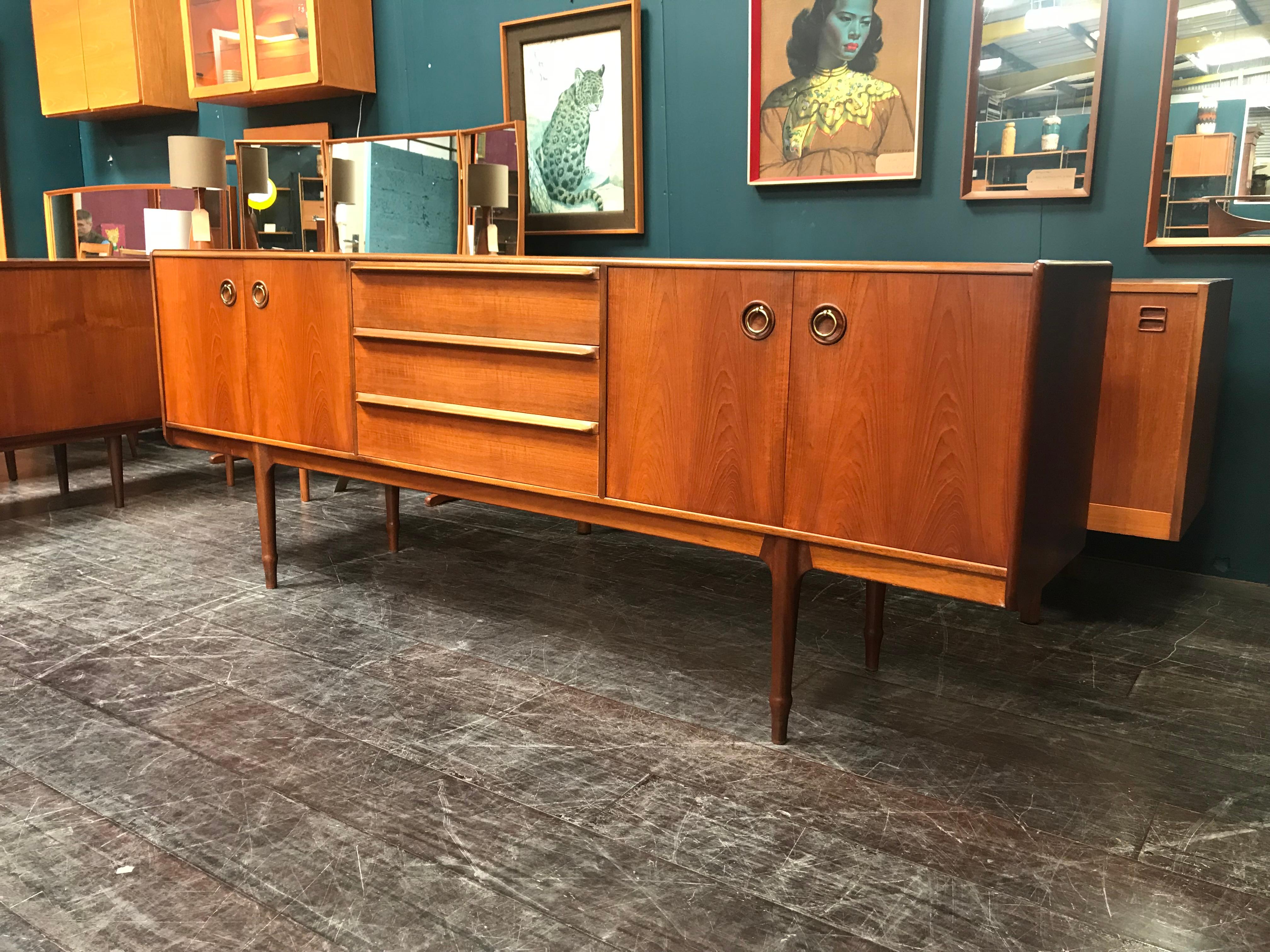 A vintage teak sideboard designed by Tom Robertson and manufactured by A.H. McIntosh of Kirkcaldy. This is a rarely found piece of midcentury Scottish furniture and features extensive storage. The sideboard has two shelved double cupboards that sit
