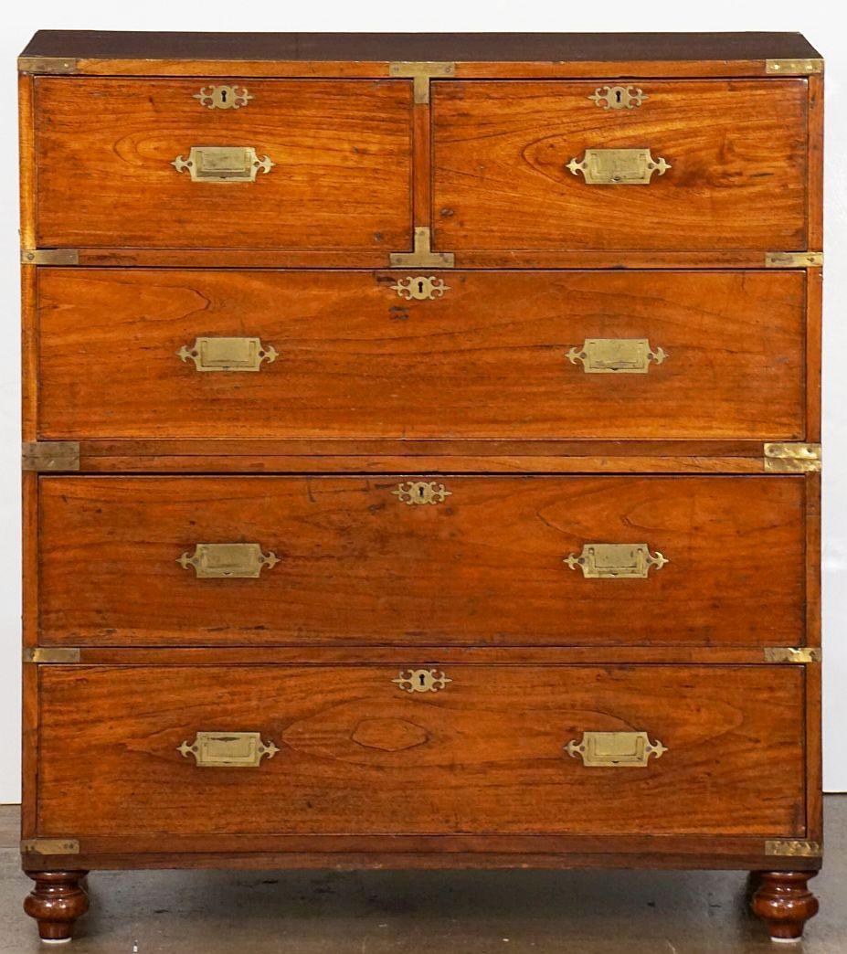 A superb British military officer’s Campaign Ware chest of drawers or dresser, from the 19th century, featuring a patinated mahogany exterior, showing two short drawers over three long drawers, each with decorative brass escutcheons. The brass-bound