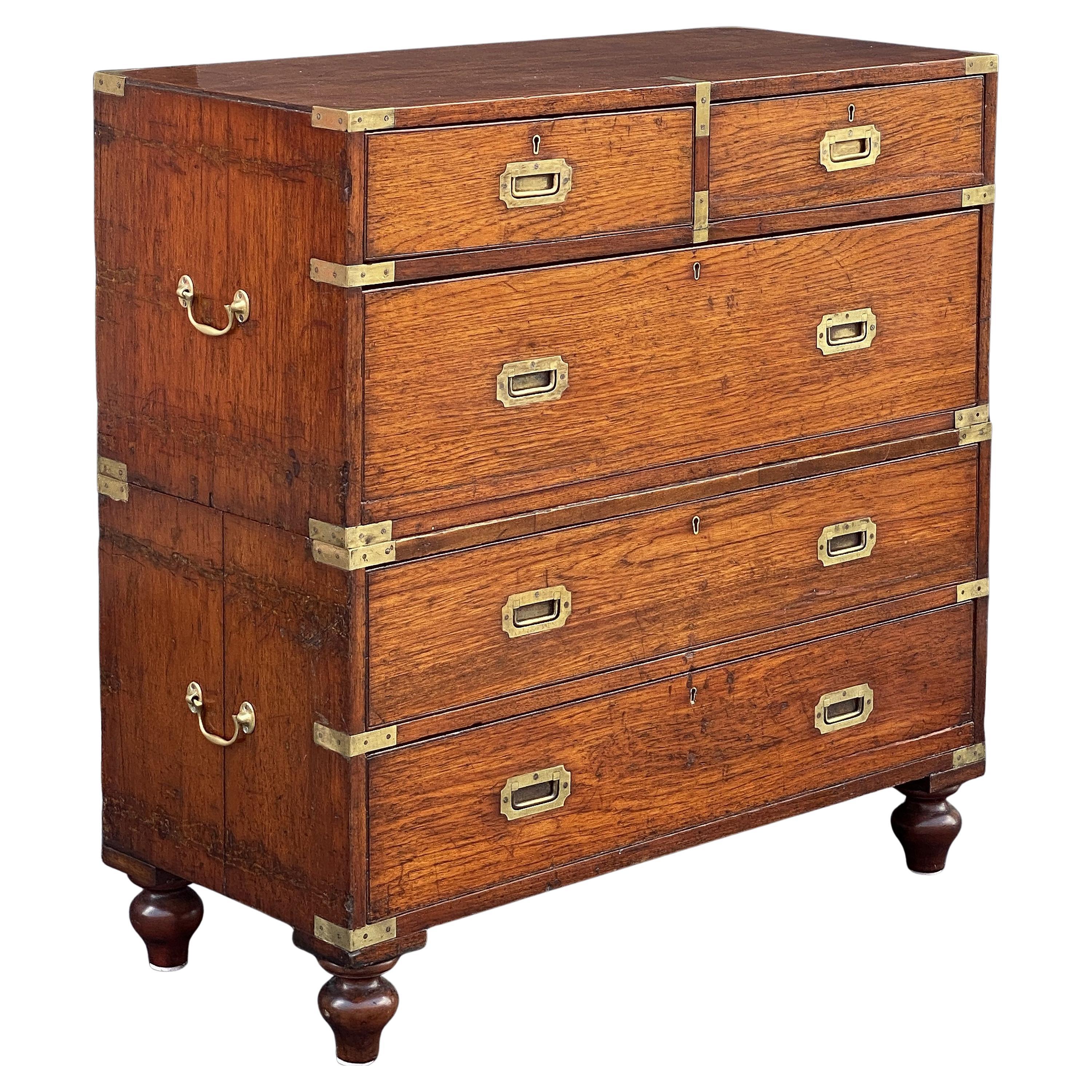 A handsome British military officer’s Campaign Ware chest of drawers or dresser, from the 19th century, featuring a patinated teak exterior with two short drawers over three long drawers, with brass escutcheons and recessed pulls. The brass-bound