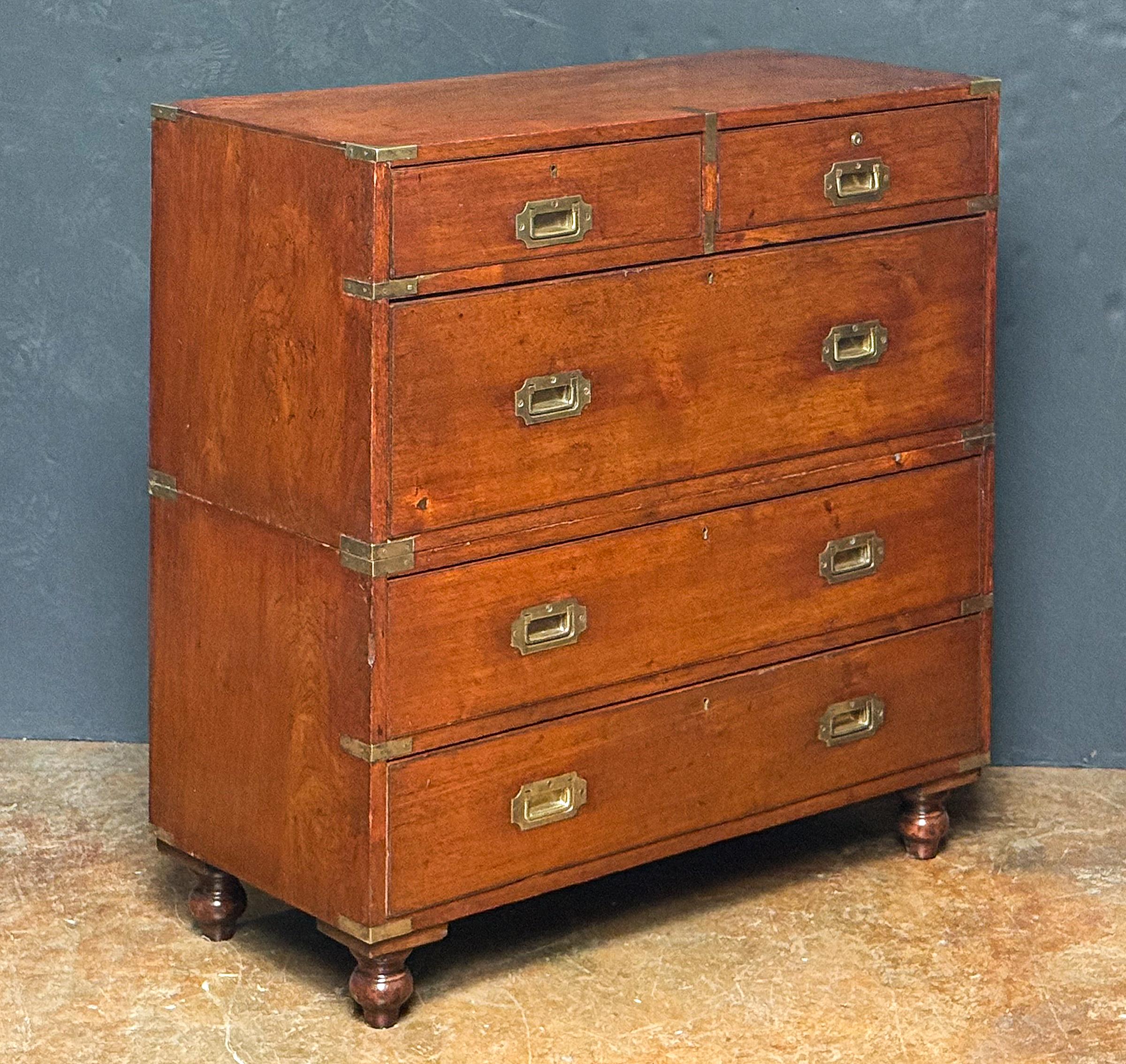 A handsome British military officer’s Campaign Ware chest of drawers or dresser, from the 19th century, featuring a patinated teak exterior with two short drawers over three long drawers, top two drawers with brass escutcheons, all drawers with