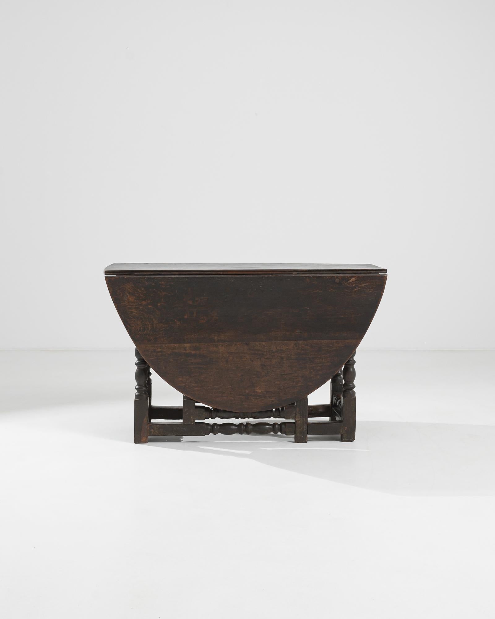 A gateleg table from the United Kingdom, circa 1900. Developed in England in the 16th Century, the gate leg table was an early marvel of space saving innovation. This example is crafted in characteristic oak. A round beveled top balances upon