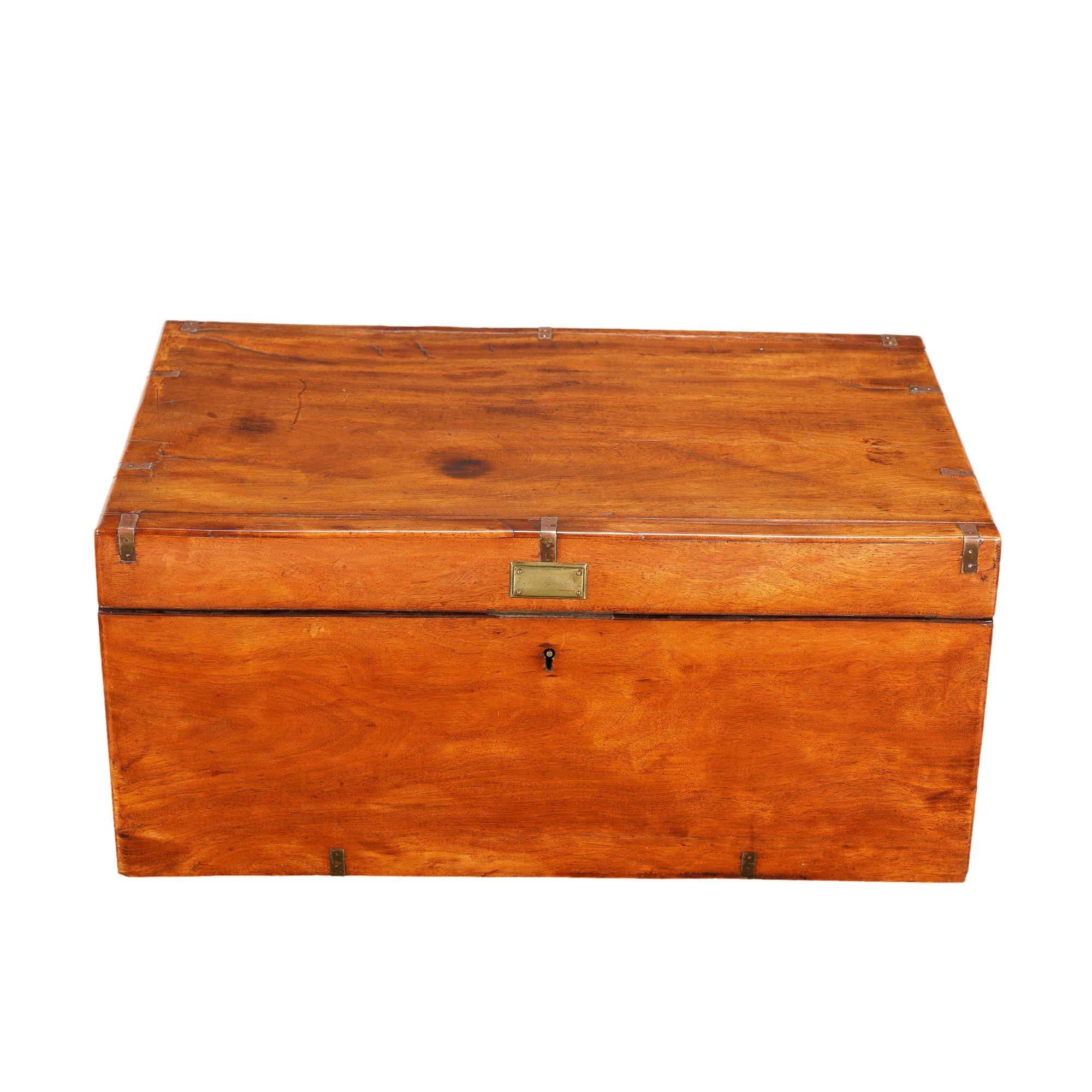 British officers foot locker in mahogany with brass strap reinforcements and an exceptionally thick, reinforced lid. The brass plate above the lock on the face of the trunk is engraved with the name 
