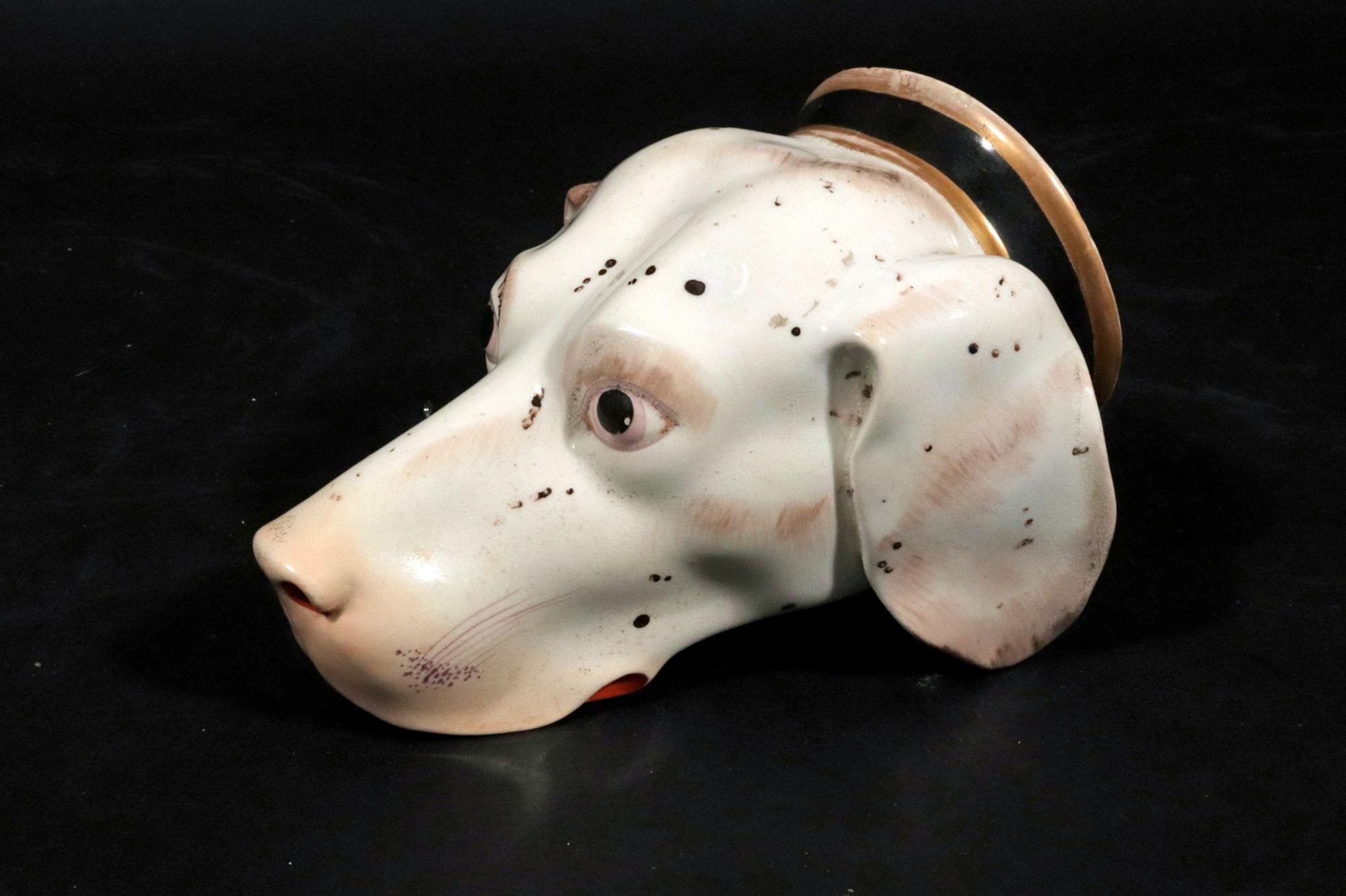 British Porcelain Large Stirrup Cup of a Hound,
Circa 1820

The English porcelain stirrup cup is in the form of a hound head.  It is naturalistically modelled with a white and reddish brown marking with black scatted spots with log ear extending