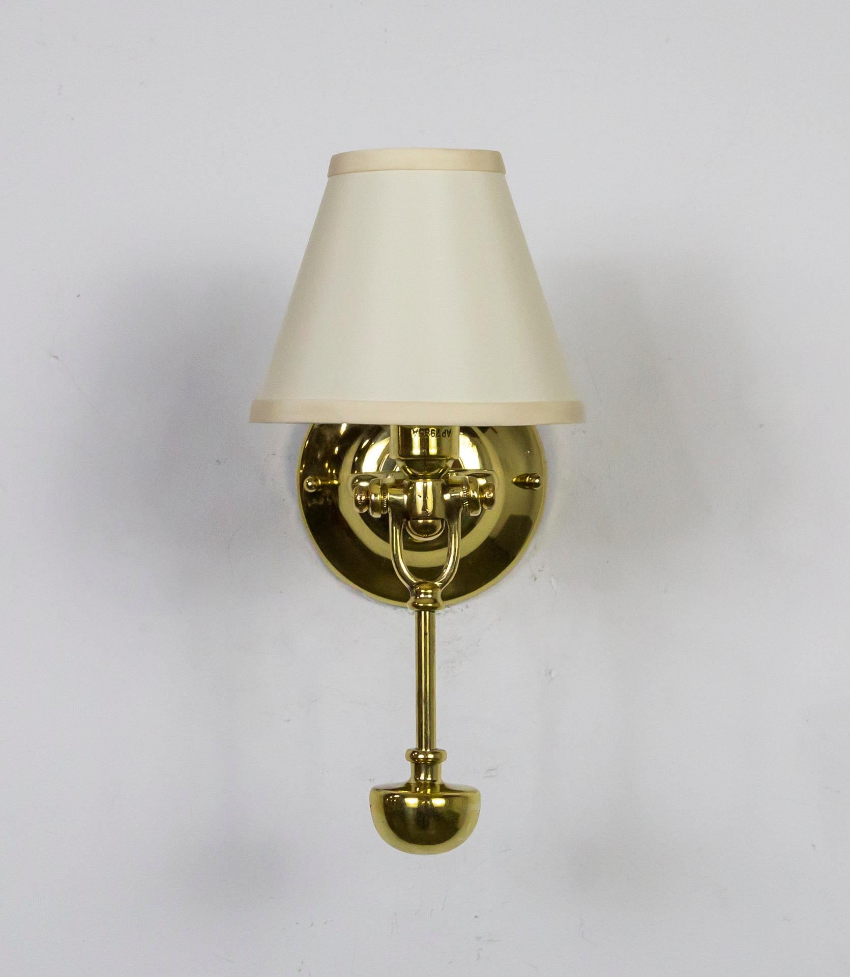 A pair of nautical, candlestick style sconces from the late 19th century. Made of solid brass in Britain as gimbal wall lights for a ship. Sold with ivory colored silk, hard-back, empire shades. Newly wired, buffed and polished. The gimbal action