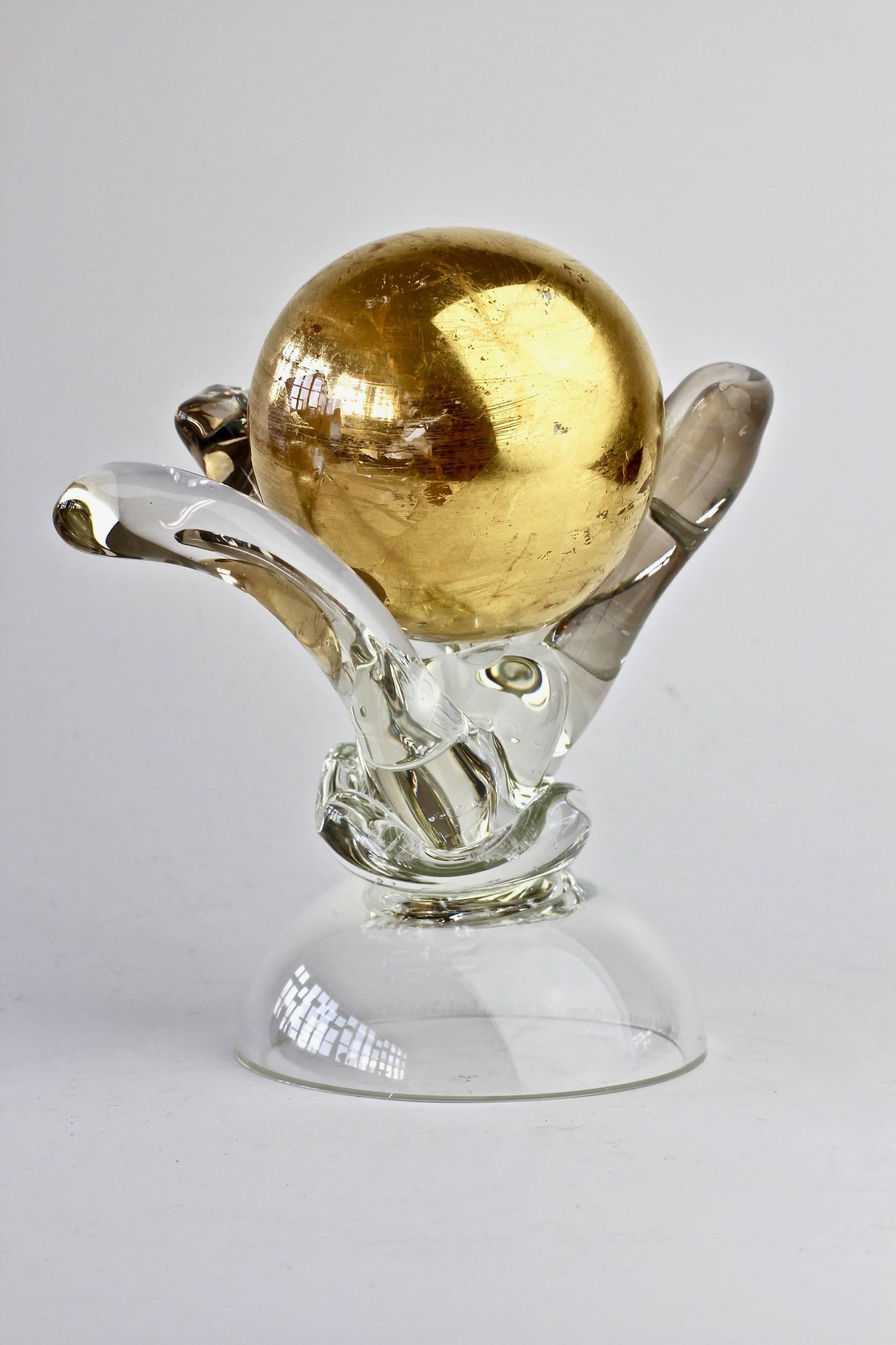 Unusual and quirky art glass sculpture signed by British glass artist and maker Adam Aaronson, England, 1997. Elegant and organically formed holding a 'golden globe' gilded glass ball. 

This was produced 1997 - in the middle of Adam Aaronson's
