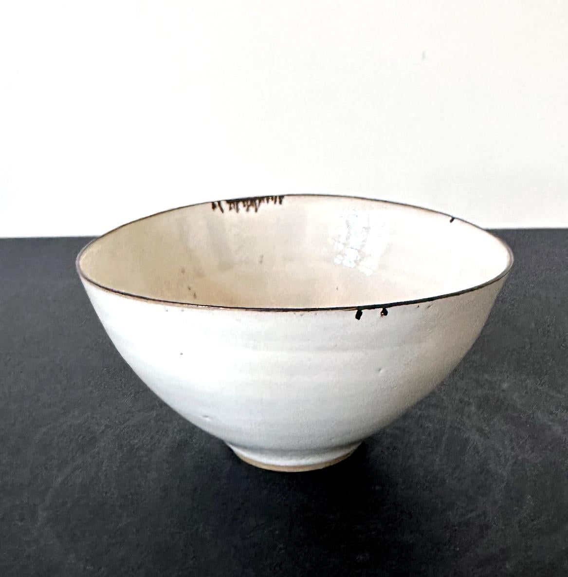 Cuenco de cerámica de estudio realizado por Dame Lucie Rie (1902-1995) hacia la década de 1950. El cuenco, icónico en los repertorios del célebre alfarero británico, tiene una forma orgánica, elegantemente posada, con el cuerpo ovalado ligeramente