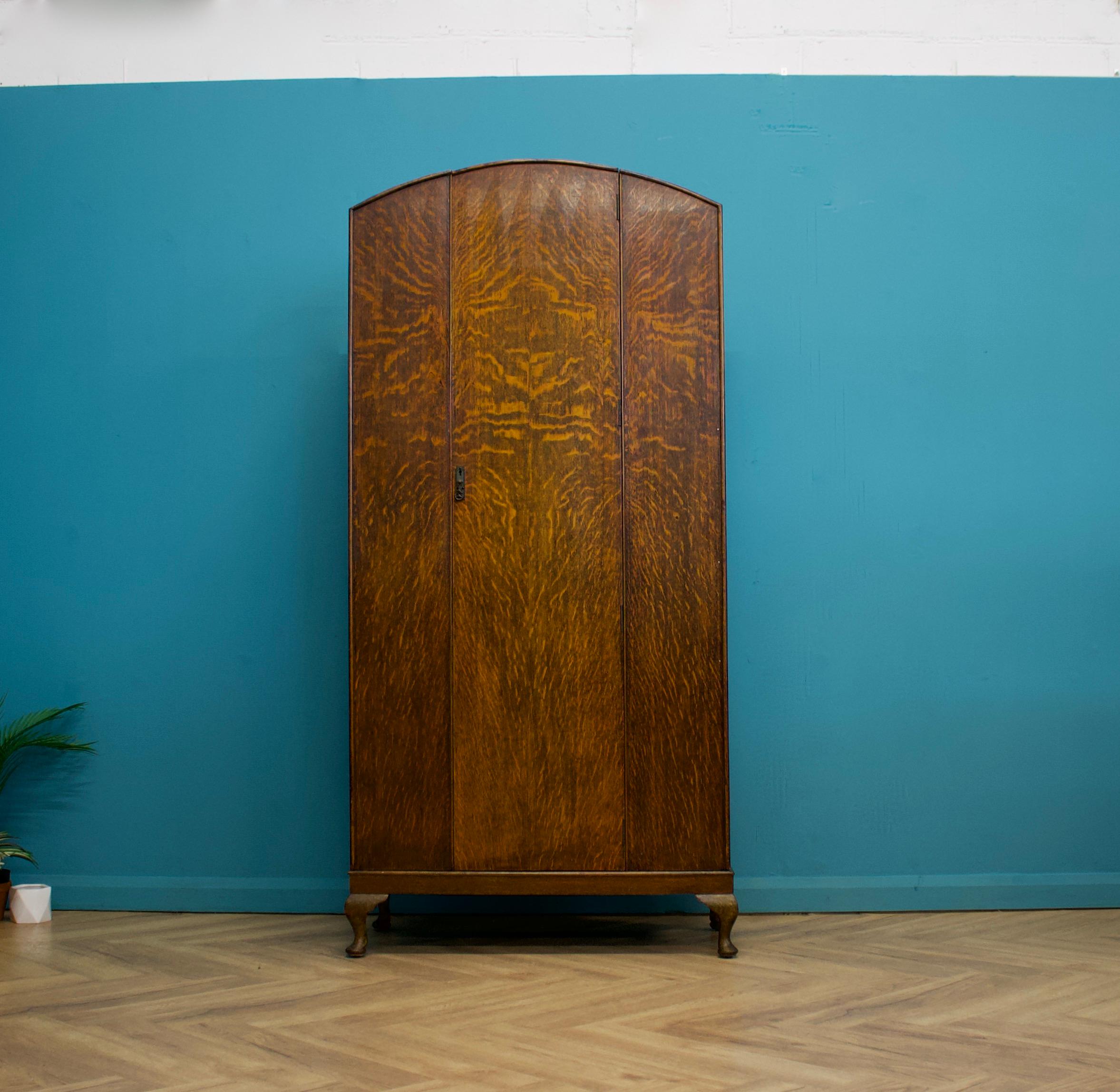 We have a domed top, freestanding oak single door wardrobe, circa 1930s

The piece stands on Queen Anne style feet

Inside there is a hanging rail, a shelf and an internal full length mirror

There are also additional brass coat hooks - the rail can