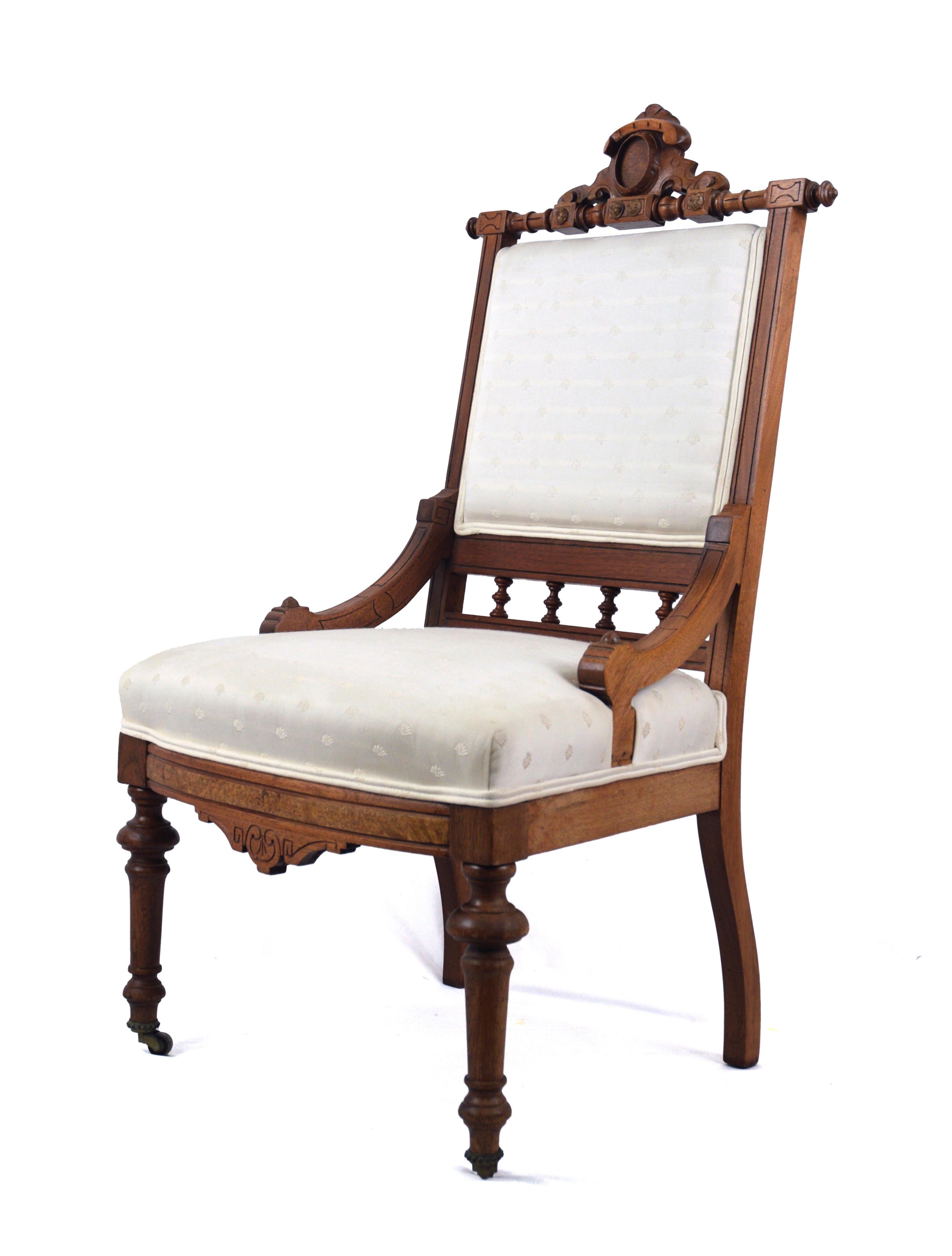 Brocade-Upholstered Eastlake Chair with Casters

Hand-carved wooden chair with off-white brocade fabric. The back and seat are matching, with double piping throughout. The front two legs feature rolling wheels but the back two legs are stationary.