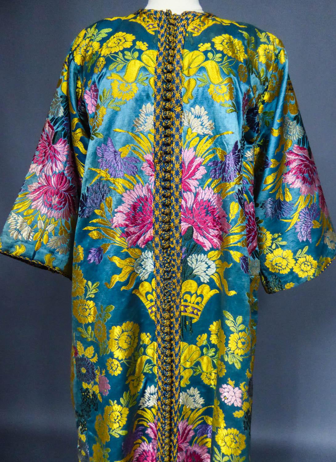 Circa 1900
Morocco or Middle East

Flamboyant Kaftan or formal coat in brocaded silk from the late 19th century. Rich decor with large floral bouquets fuchsia, pink, purple, sky-blue and green on blue satin of France. Buttong in front with yellow