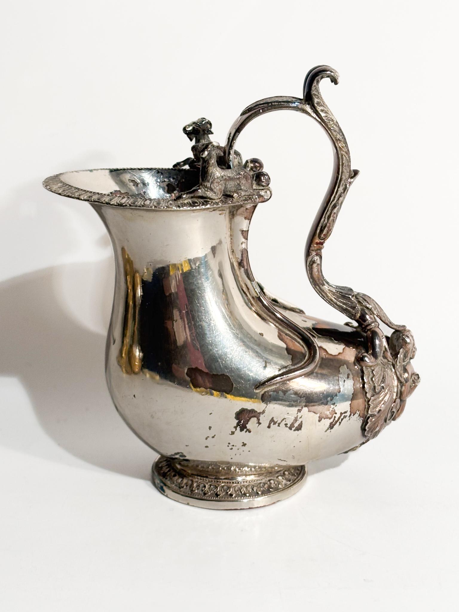 Brocca in argento inglese, realizzata a Londra nei primi anni del XIX Secolo. Forma classica delle brocche greco-romane, base circolare, manico sagomato con attacco terminante a cherubino, due capre sul bordo. 

Ø cm 15 Ø cm 14 h cm 7