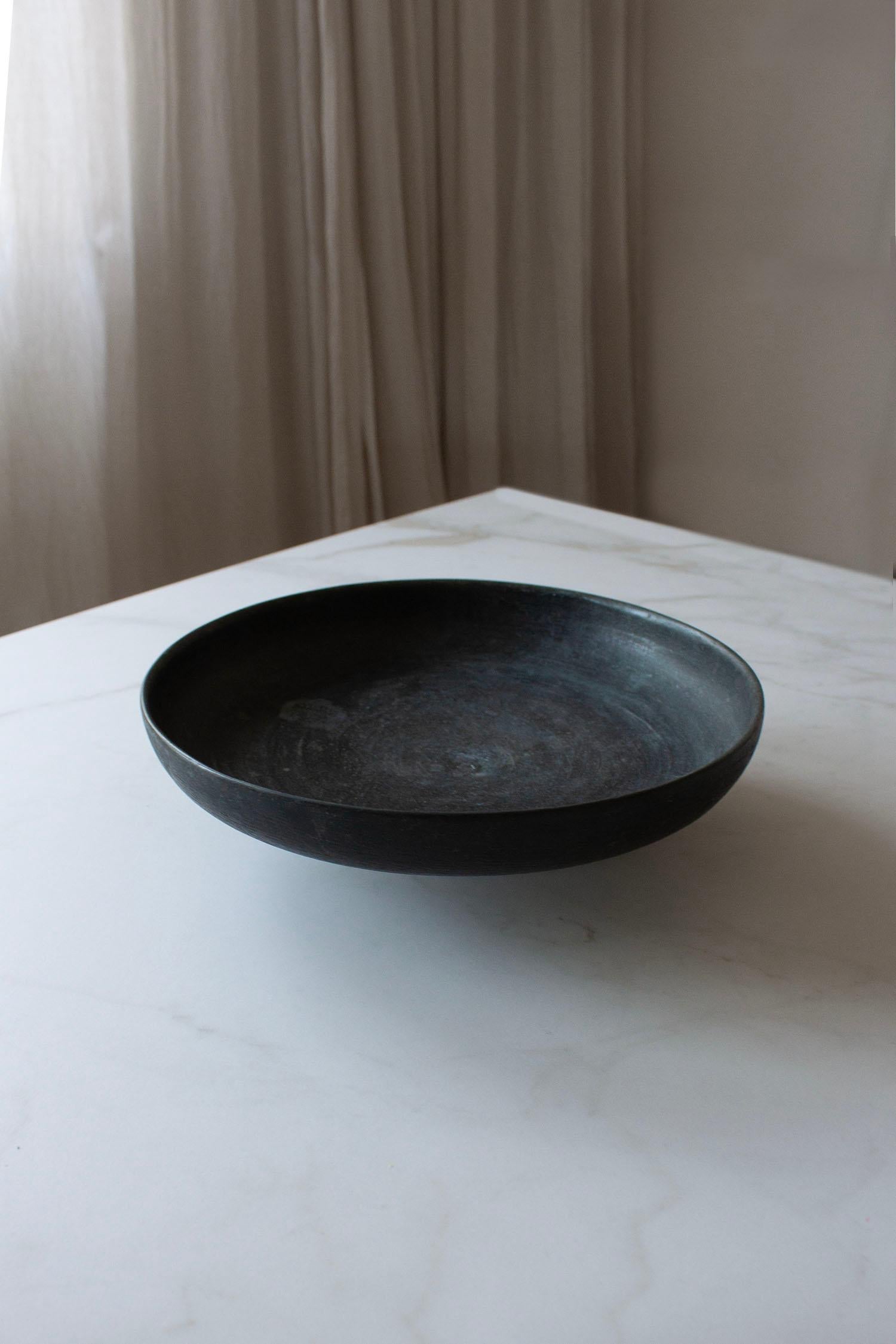 This bronze footed bowl has a simple yet striking presence. Its shallow form rests on a small pedestal, giving it a balanced, elevated look. The surface carries a natural patina, which adds depth and character to the piece.

It works beautifully as
