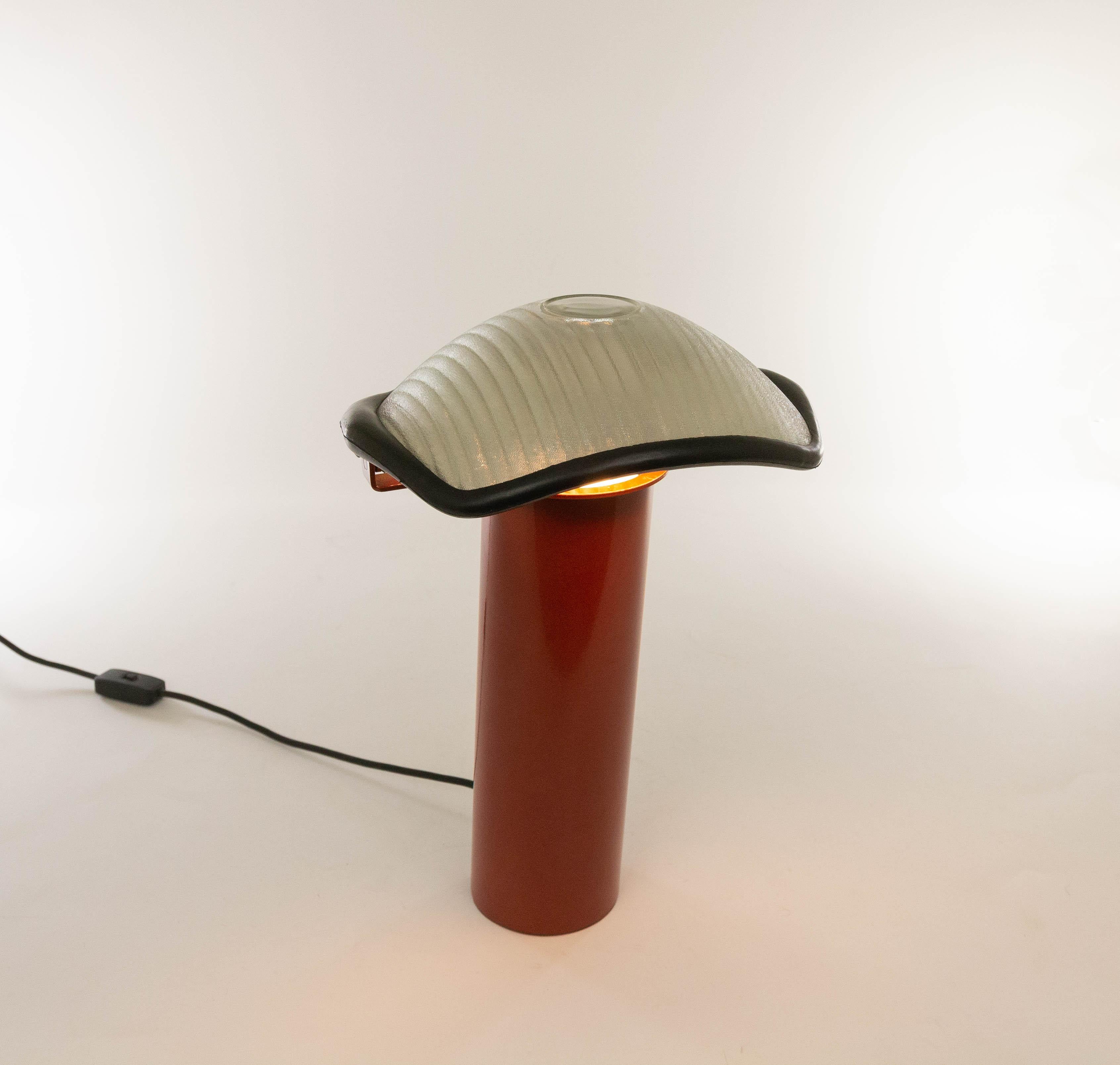 An exceptional table lamp model Brontes, designed by Cini Boeri and produced by Artemide, 1981.

The model consists of a heavy red lacquered cylindrical metal base and a pivoting shade with a rubber rim. The glass shade of Brontes is silver on the