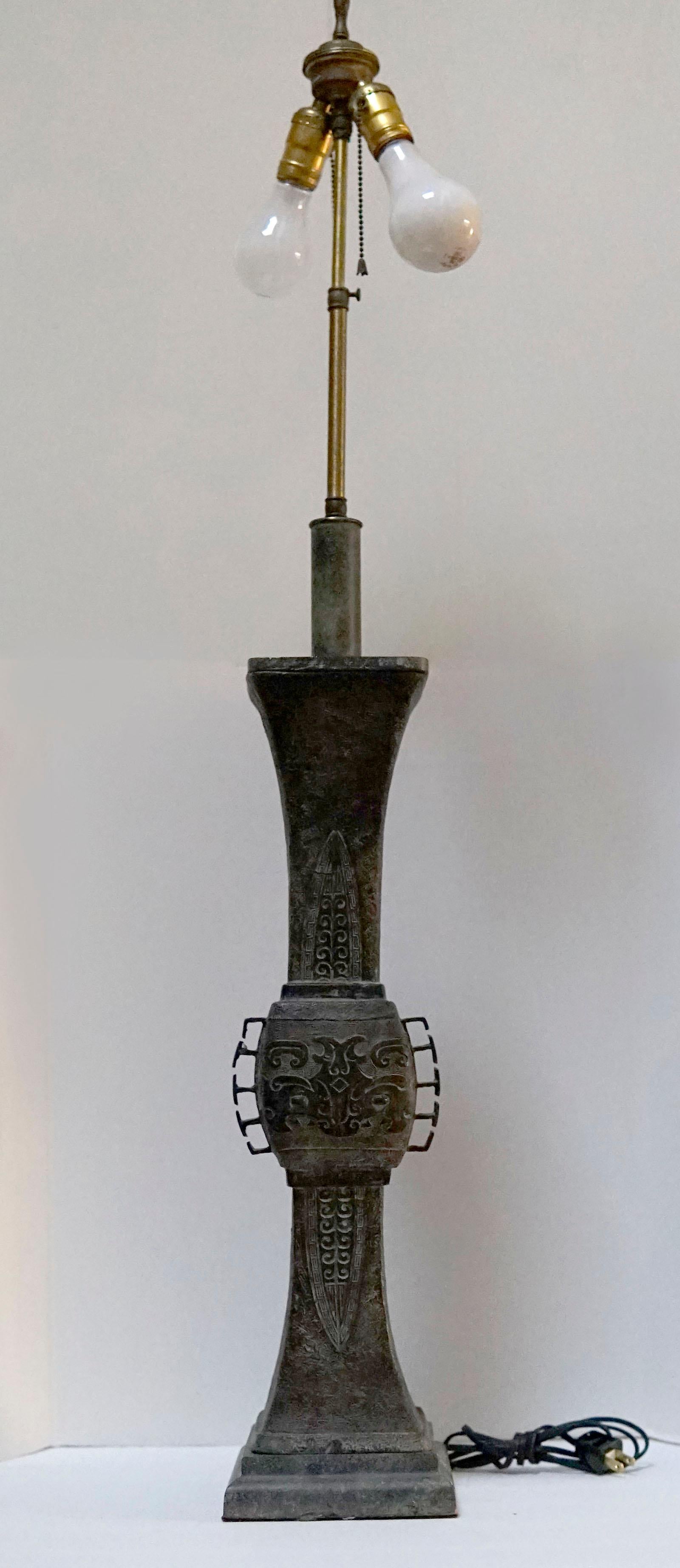 The attenuated silhouette of this late 19th century bronze table lamp turns heads. It is an antique Asian archaic style bronze. The intricate carving and the oxidized bronze color speak to age and quality. It is similar to the mid-century lamps