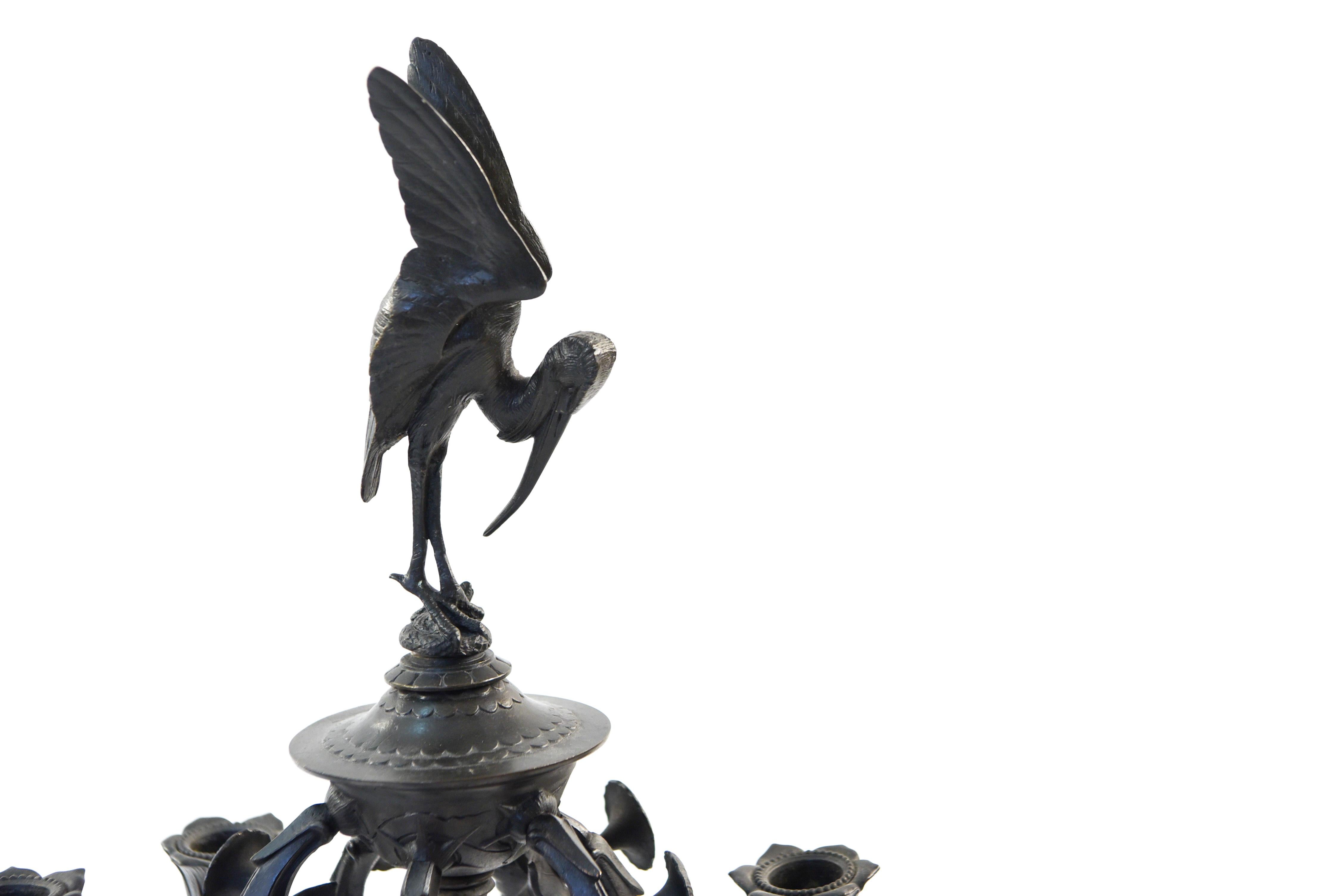 A pair of grand tour style candelabras from France, 1900s. In a patinated bronze featuring classical motifs with naturalistic animals and birds.