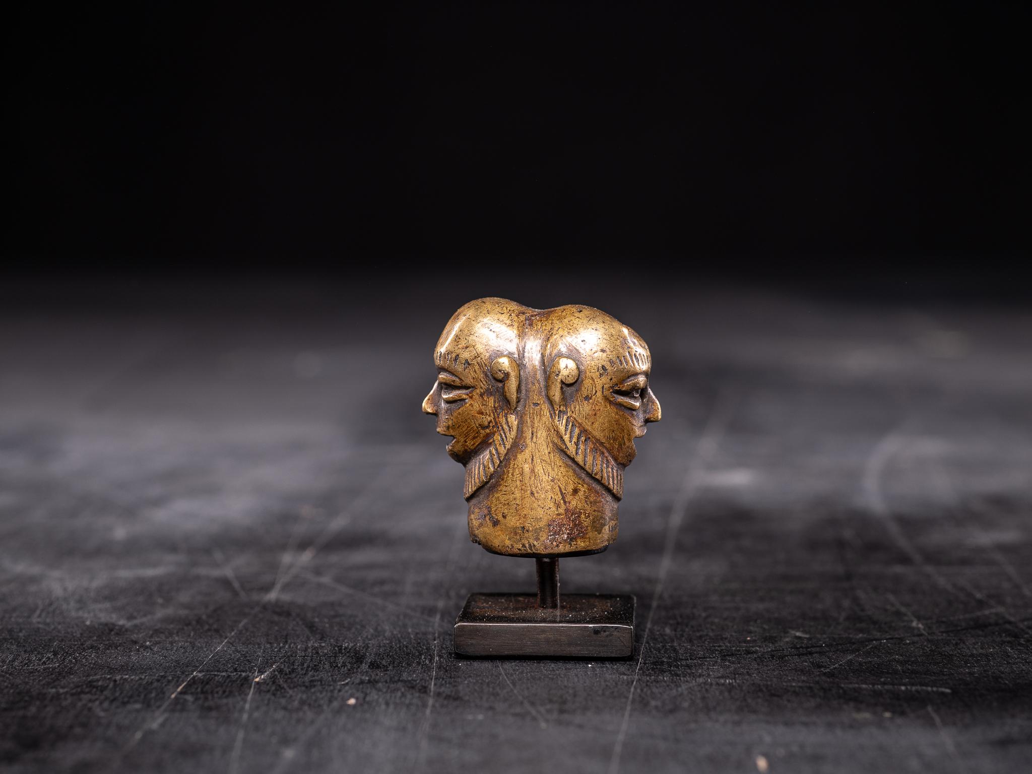 Sommet d'un sceptre sculpté en alliage de bronze avec deux visages identiques sur les deux faces. Belle patine d'usage naturelle. Base incluse dans le prix.