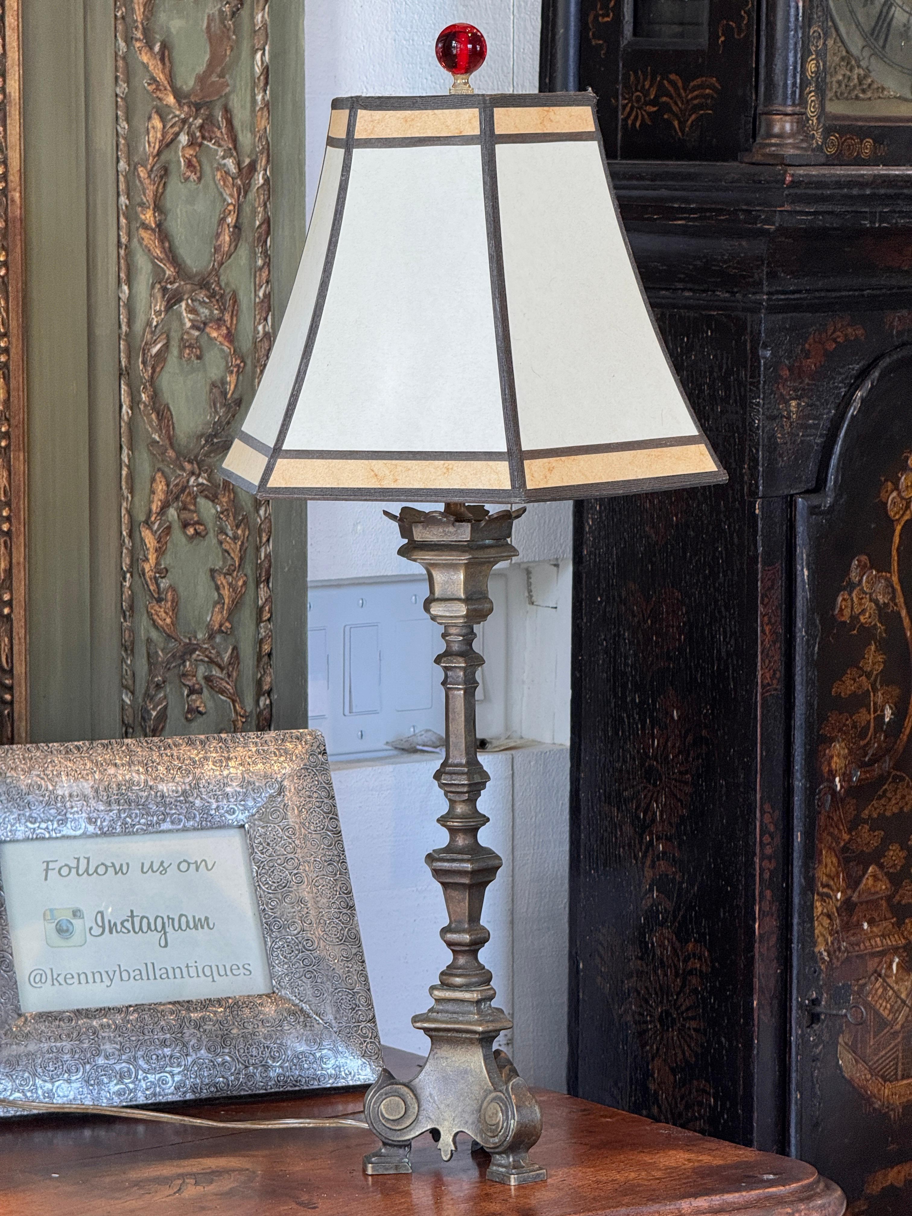 Bronze altar stick converted to a table lamp, featuring a stepped and scrolled tripod base with classical detailing. The sculptural form and aged patina highlight its ecclesiastical origin and solid bronze construction. A handsome and weighty piece