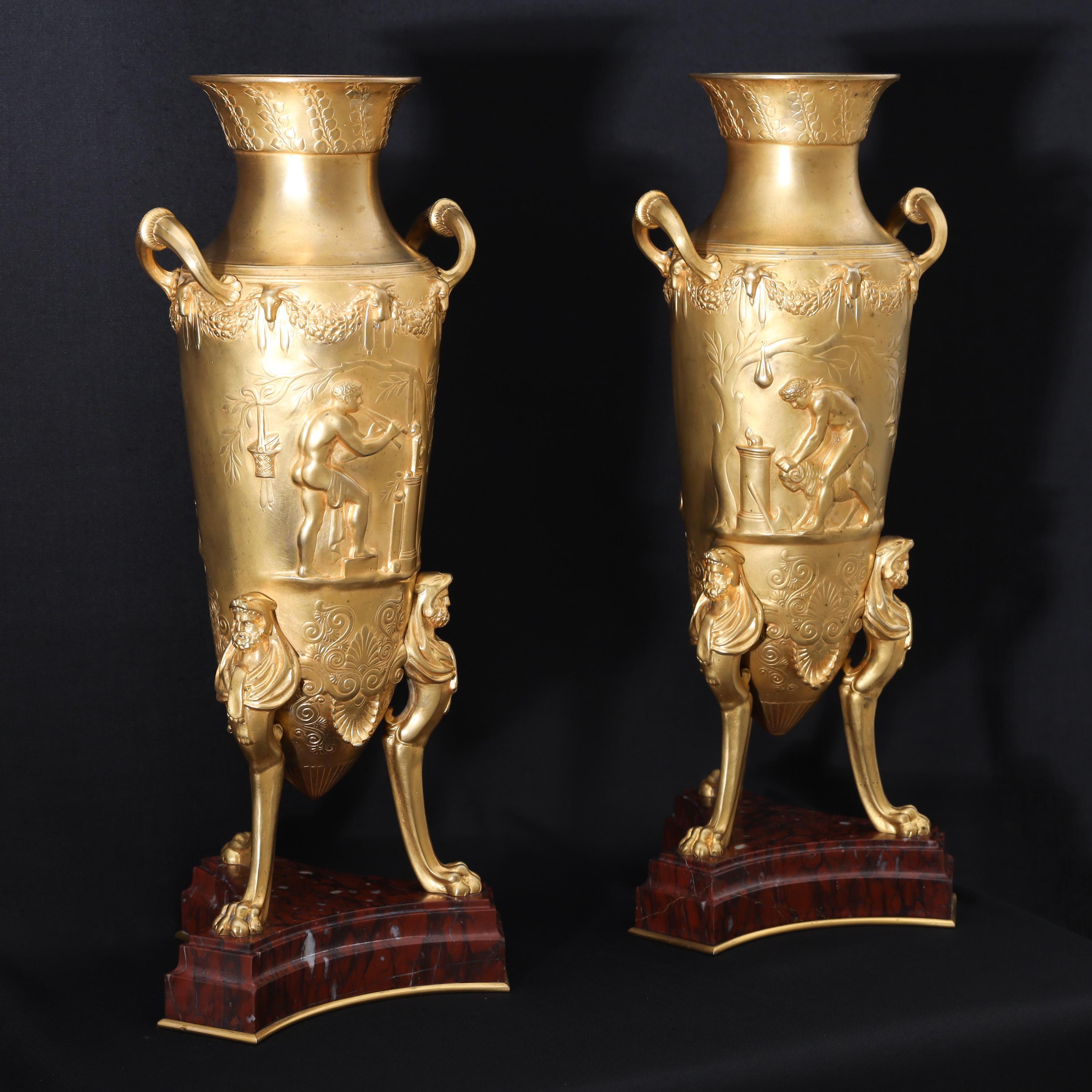 Pair of fire-gilt bronze amphorae by Ferdinand Levillain (1837-1905) and Ferdinand Barbedienne (1810-1892) on trefoil red marble bases. The vases stand on lion paw feet with Hercules atlases and antique scenes in low relief on the walls. Stamped on