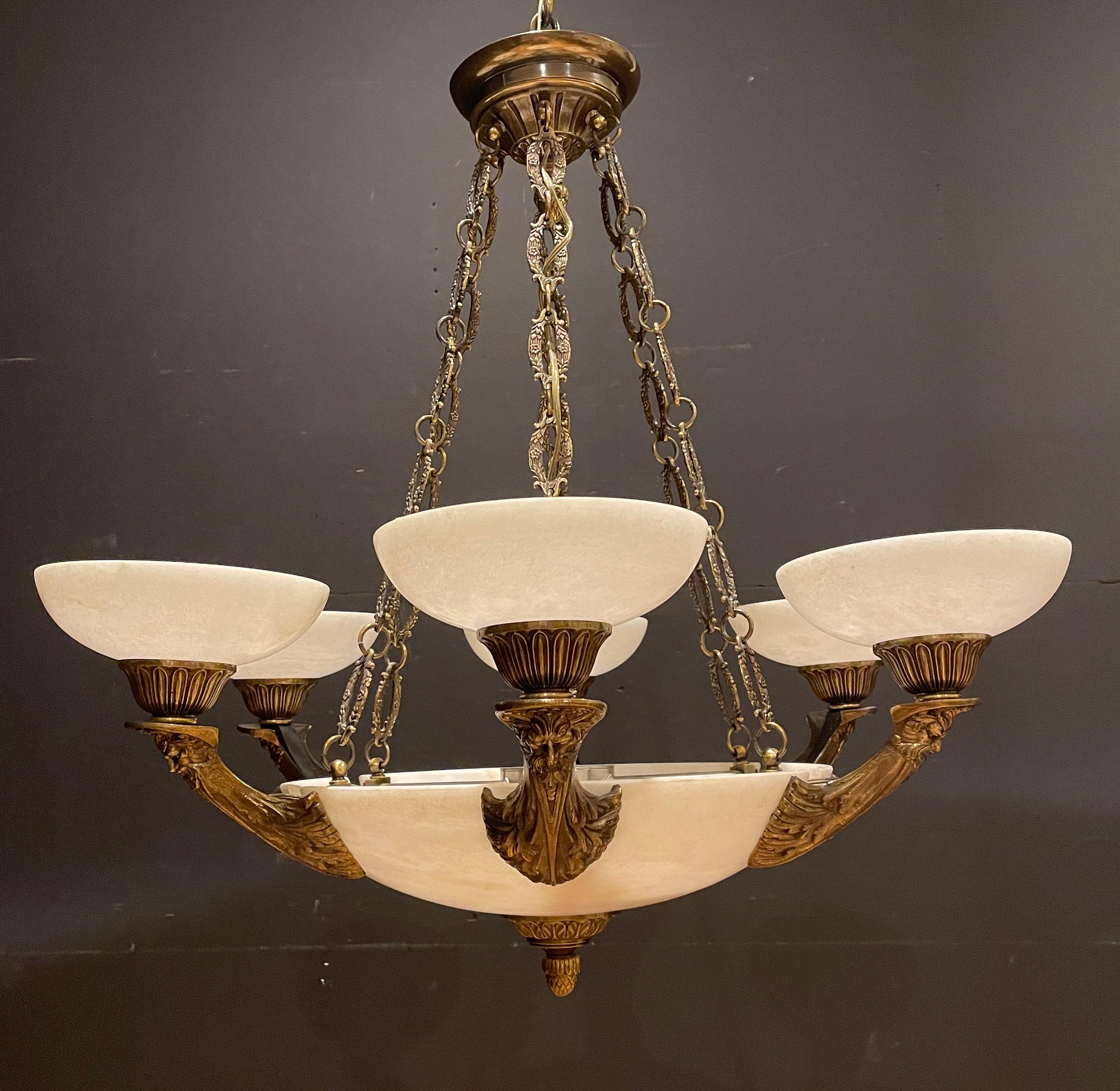 Fine quality white alabaster and patinated figural bronze chandelier. Center alabaster dome pendant supporting six bronze arms with Zeus form masks and alabaster dome shades.