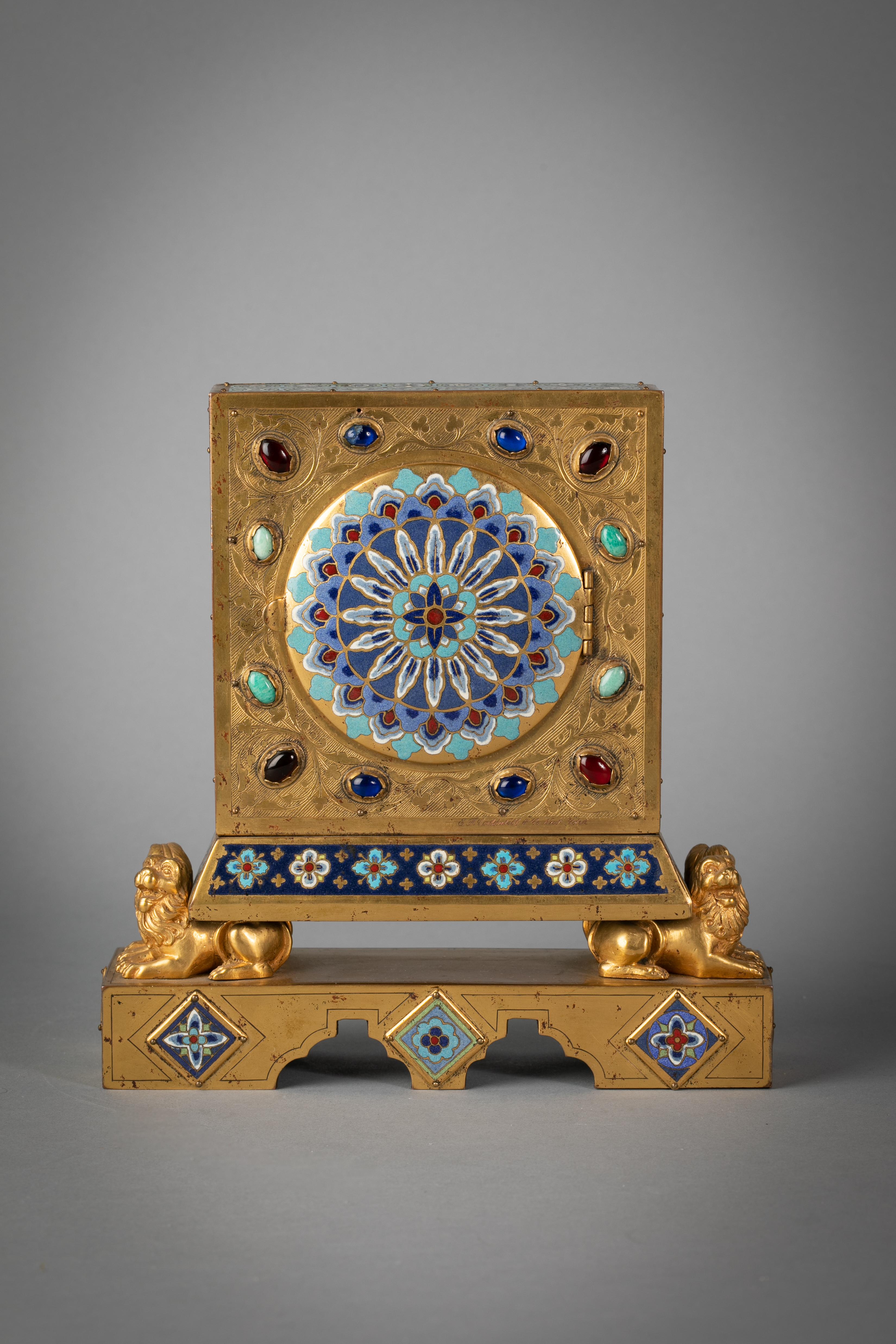 The face of the clock surrounded by eight applied panels (four round and four rectangular), All surmounted on the backs of four lions, above a platform with additional applied plaques, the back similarly decorated and studded with stones. Signed