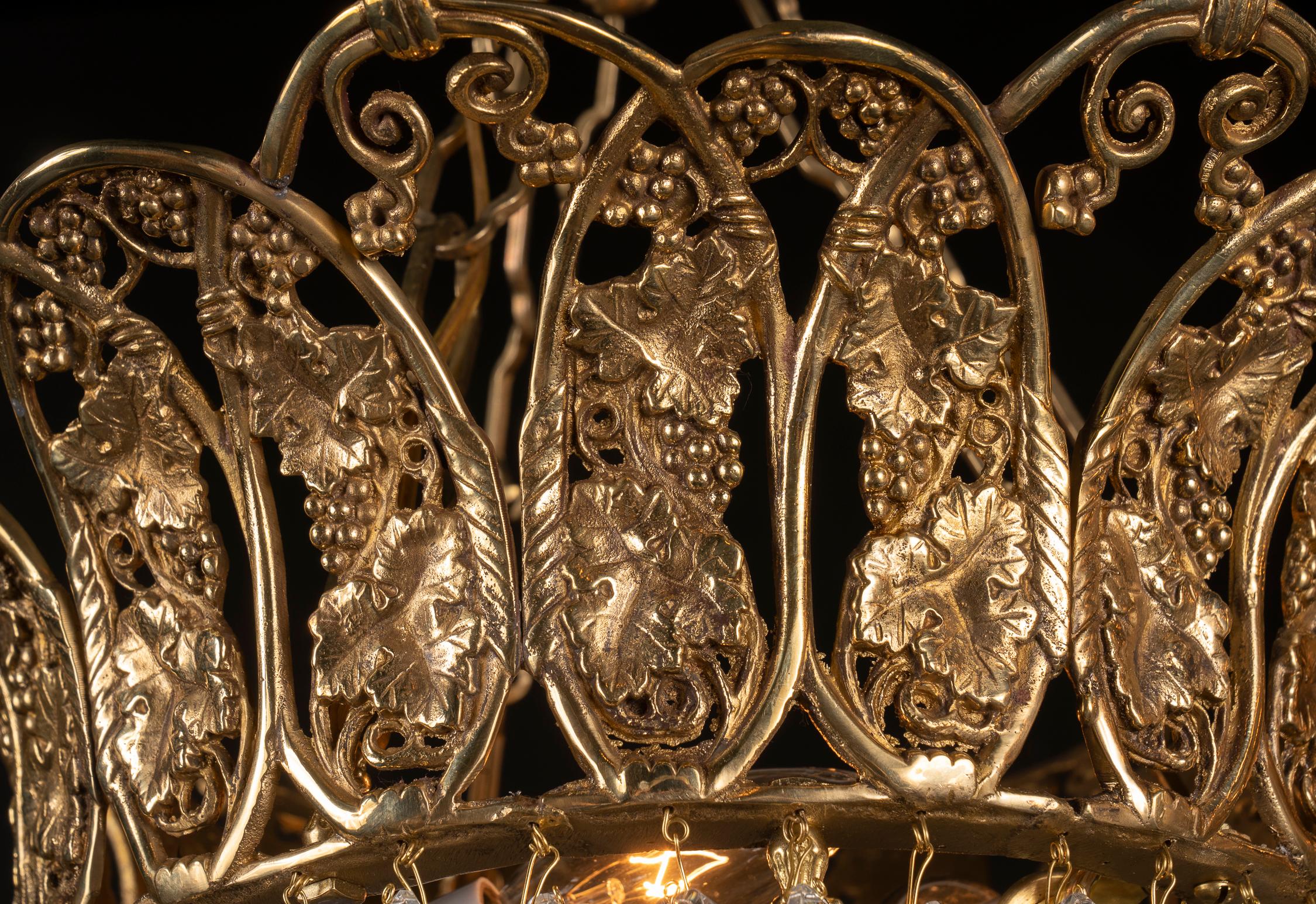 Dieser wunderschöne französische Kronleuchter aus dem frühen 20. Jahrhundert besticht durch seine fantastischen Kristallarbeiten und die kunstvoll verzierte Krone. Die Krone zeigt ein Traubenmotiv in Anspielung auf Bacchus, den Gott des Weines.
