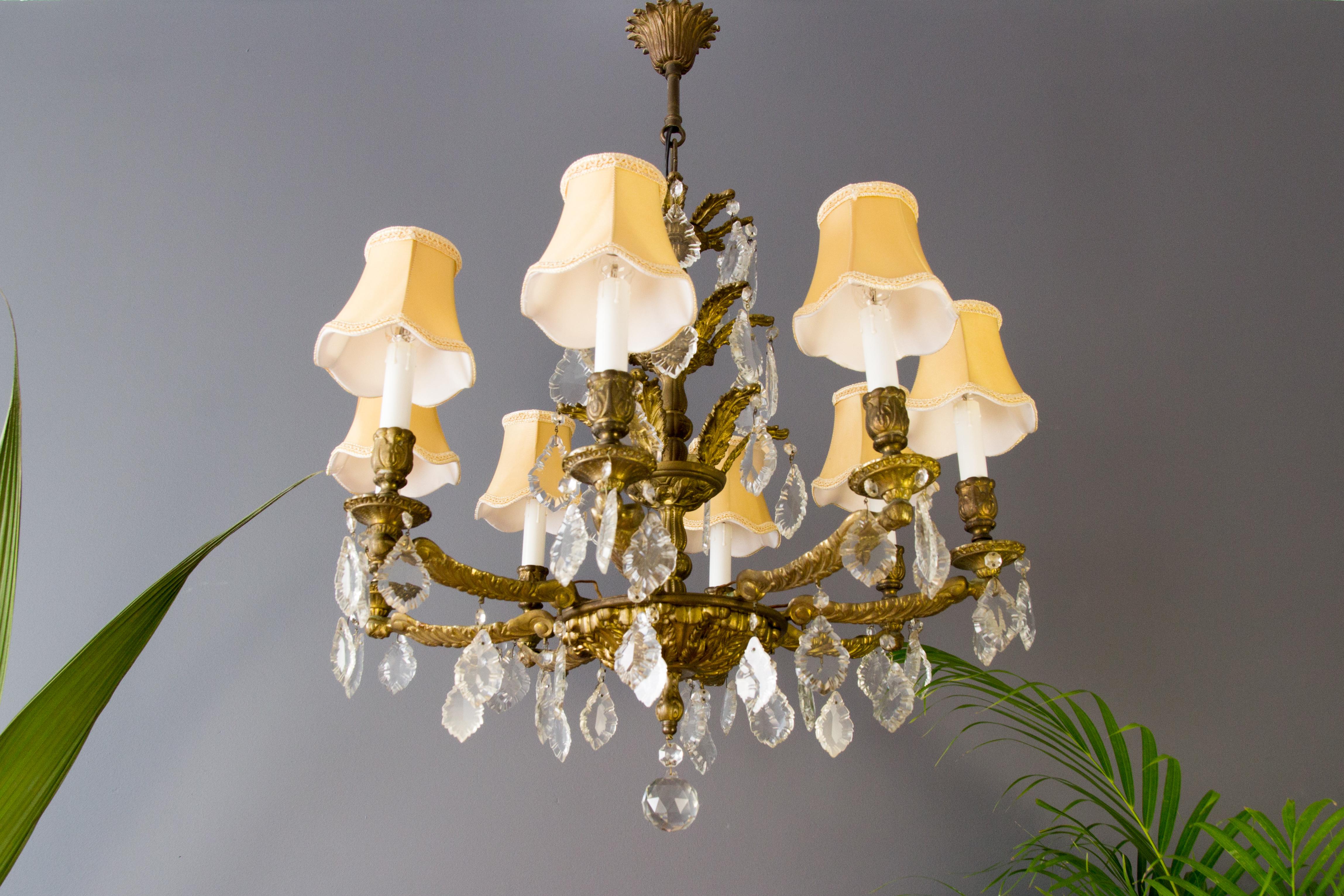 Lustre à huit lumières en bronze et cristal français avec de nouveaux abat-jour en tissu. Huit bras en bronze avec douilles pour l'ampoule E14, décorés de gouttes de cristal multifacettes et façonnées et d'une boule centrale en verre de