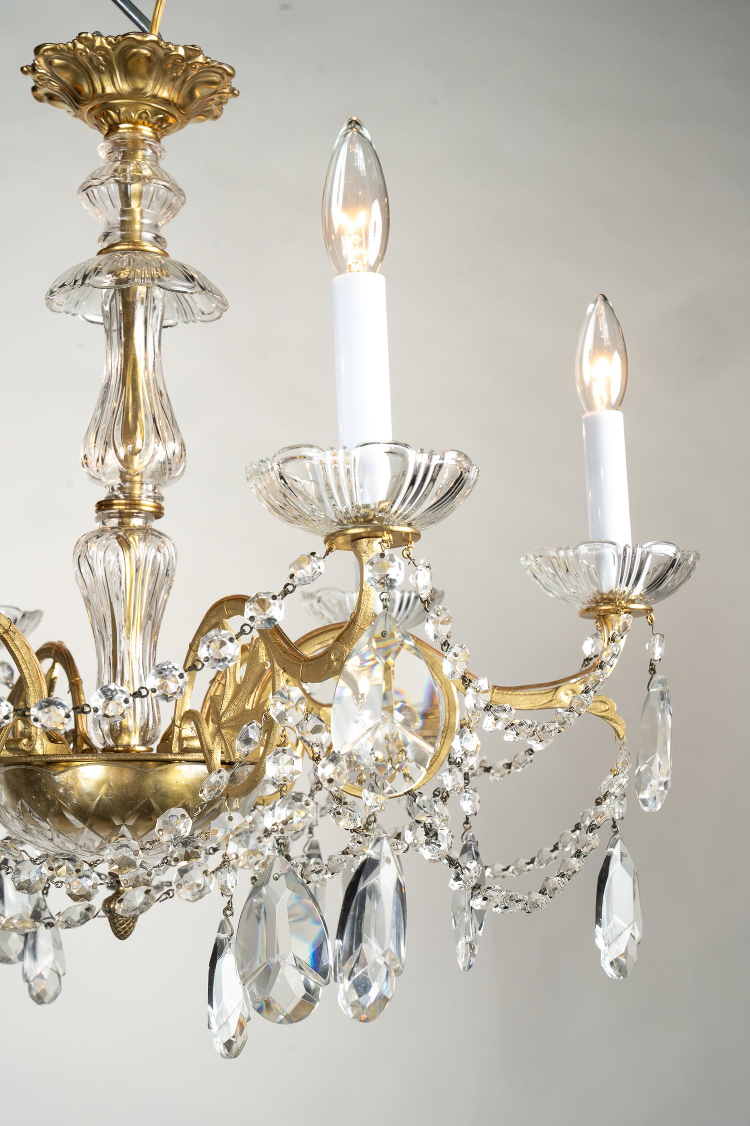 This French Louis XVI style chandelier is made of bronze, draped with beautiful crystals, and dates back to the late 19th century. The arms feature an oak leaf motif centered in the scroll work. More octagonal cut crystal drapes from arm to arm