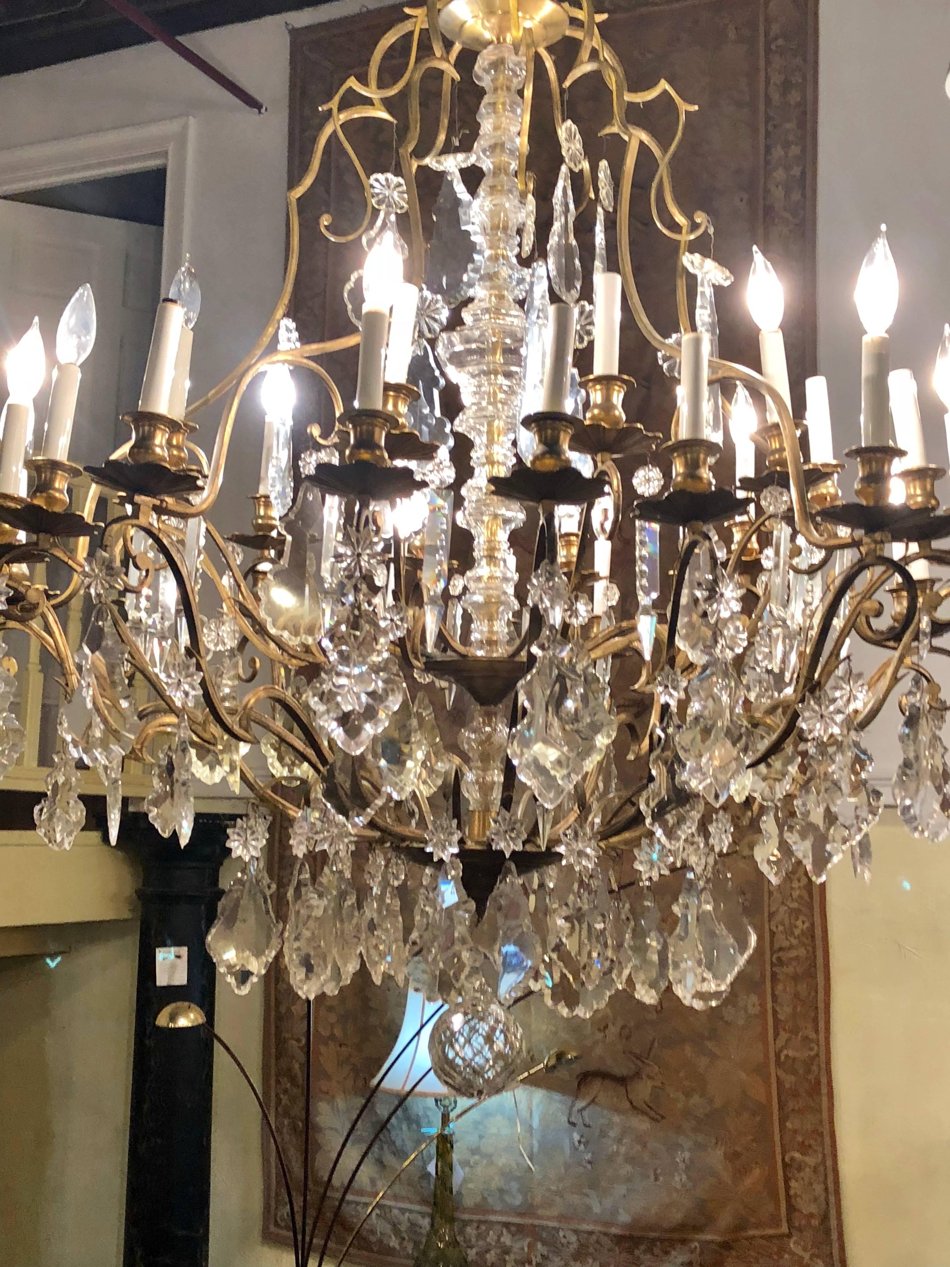 Bronze and crystal palatial thirty-light chandelier having a central column-form glass. This thirty-light chandelier has an extra long chain and matching canapé. Each antique bronze arm stemming form a center column of glass. All of the arms