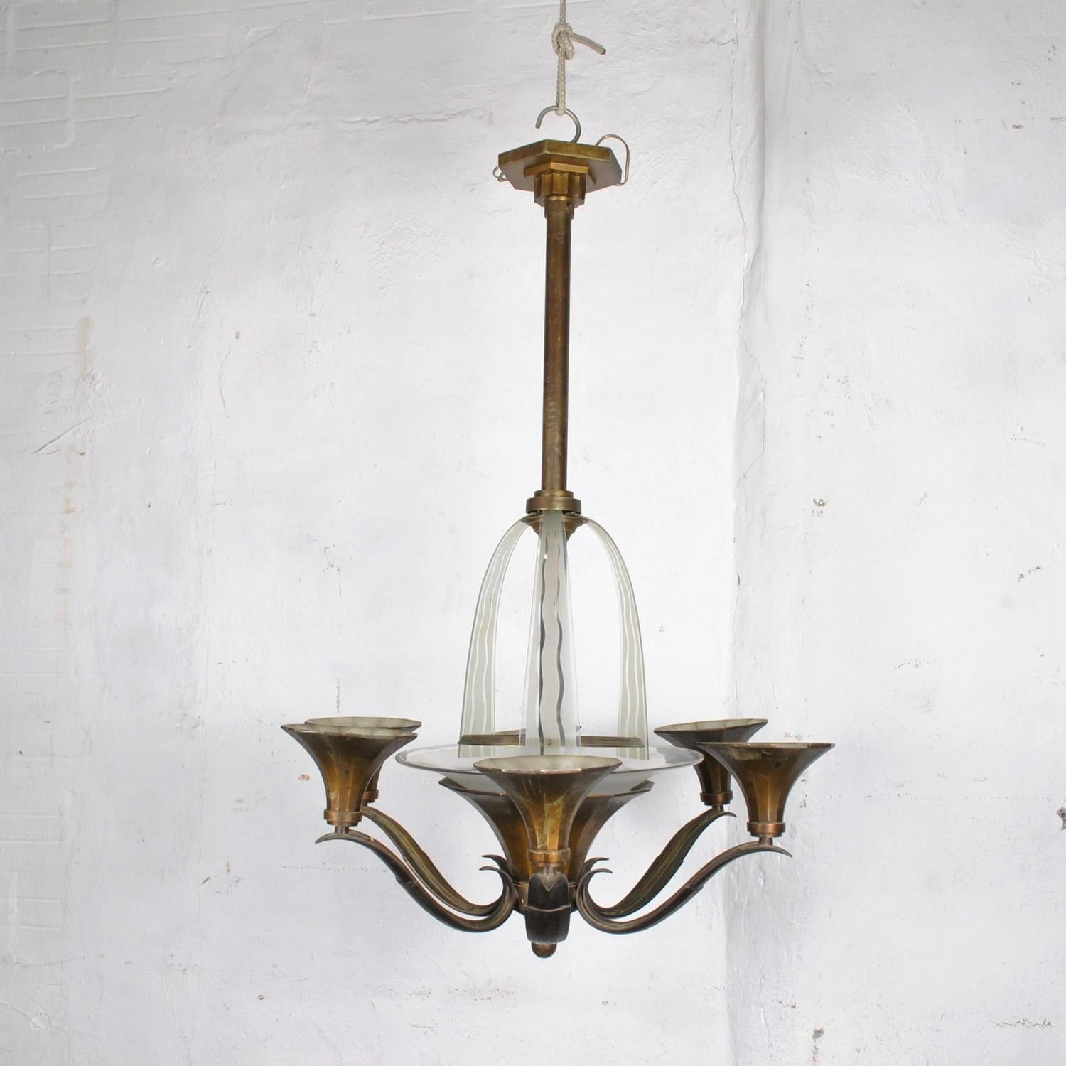 Lampadario in bronzo Art déco con una ciotola e 3 lastre di vetro opaco e trasparente, incise per creare l'illusione di una cascata

 6 luci all'esterno, 3 all'interno

Usura (lastre di vetro); bronzo con lettere/marchio

Altezza 95 cm
diametro 66