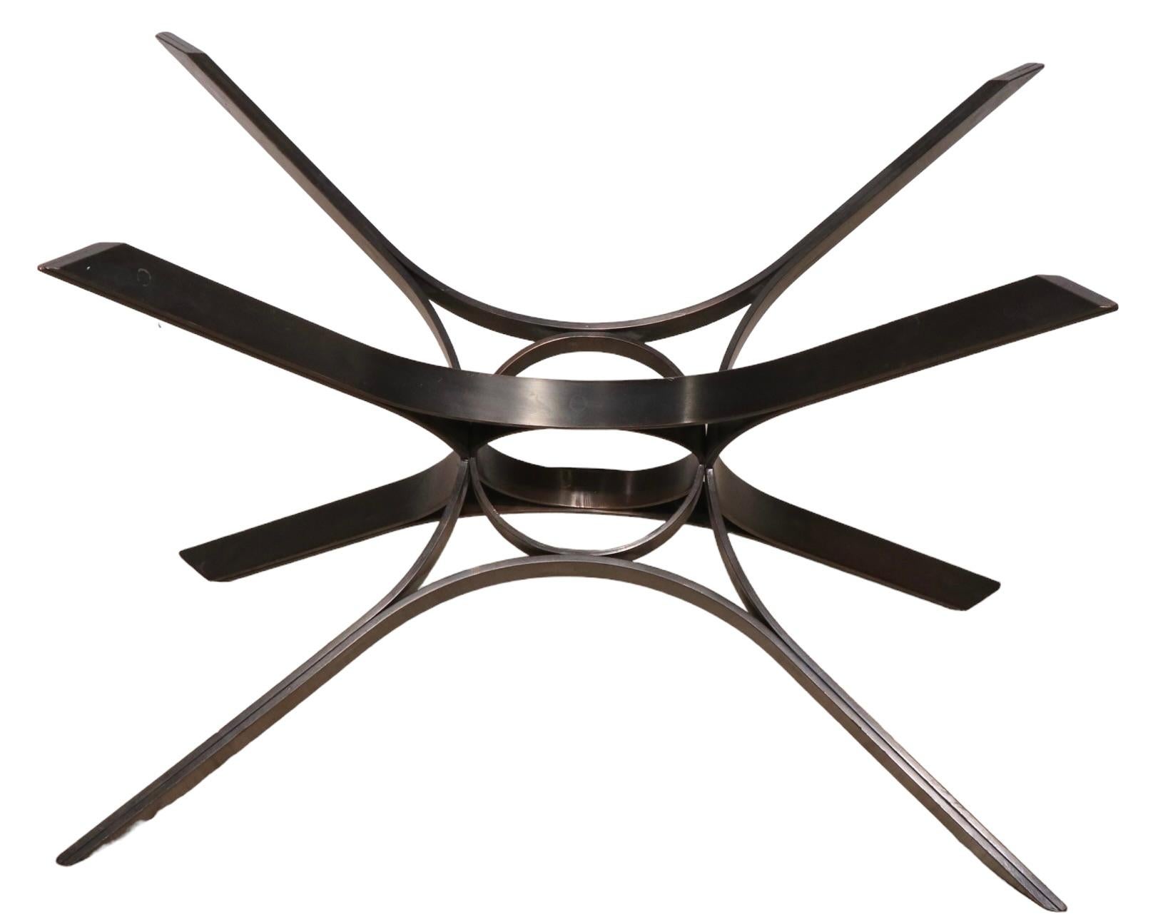 Chic, voguish, and sophisticated coffee table designed bye Roger Sprunger for Dunbar circa 1970's. This version features an architectural metal star form base of solid bronze, which supports its original tinted plate glass top. Hard to find the