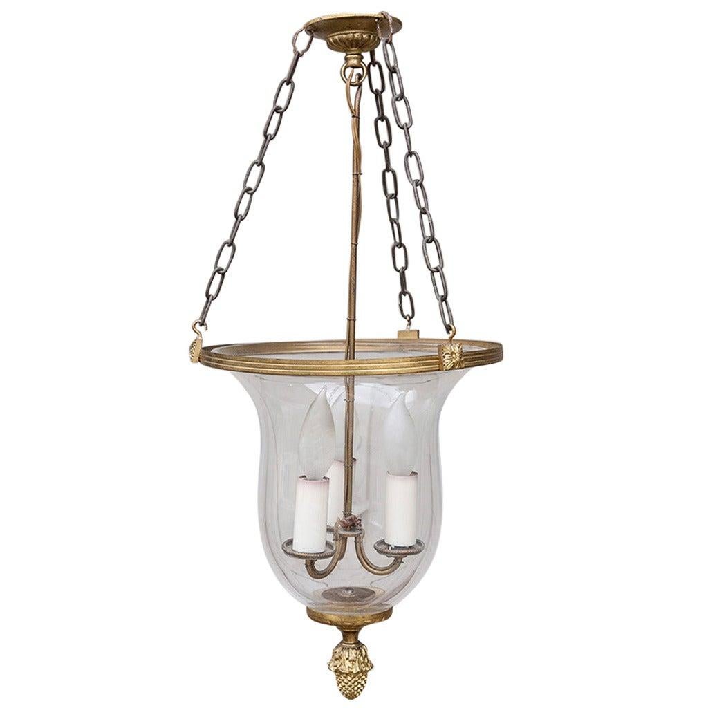 This late nineteenth century pendant light or chandelier was originally an oil lamp with three flames.  Its hand blown glass is trimmed with a gilt bronze ring at the top and is finished with a Louis XVI bronze finial at the bottom. The long bronze